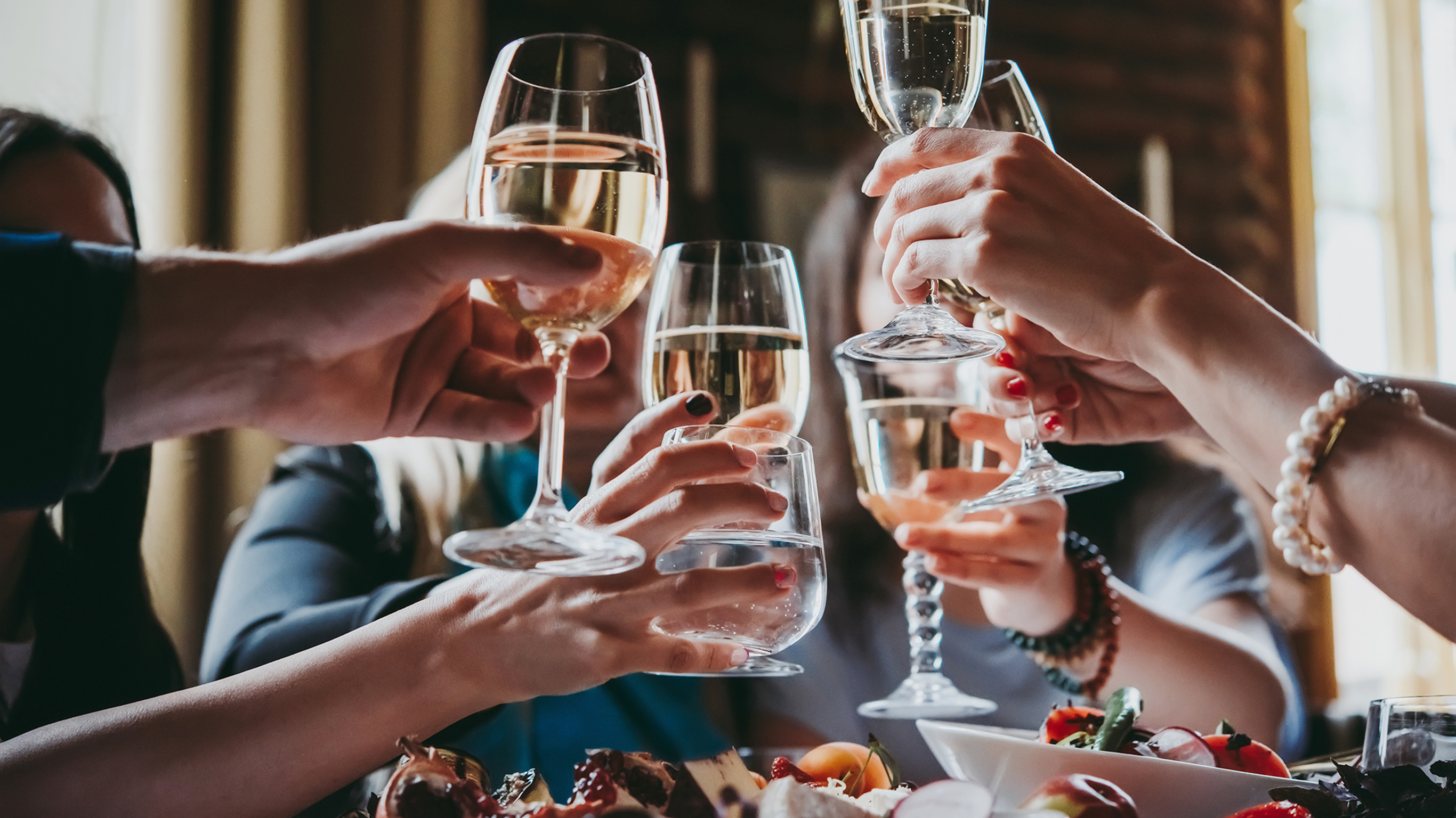A group of friends clink glasses in a bar.