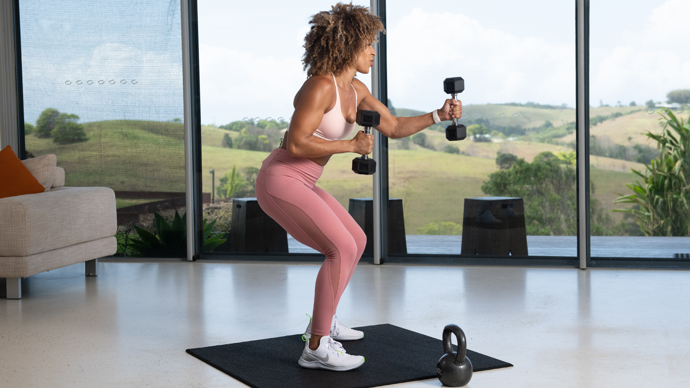 A woman squatting and punching the air with dumbbells.