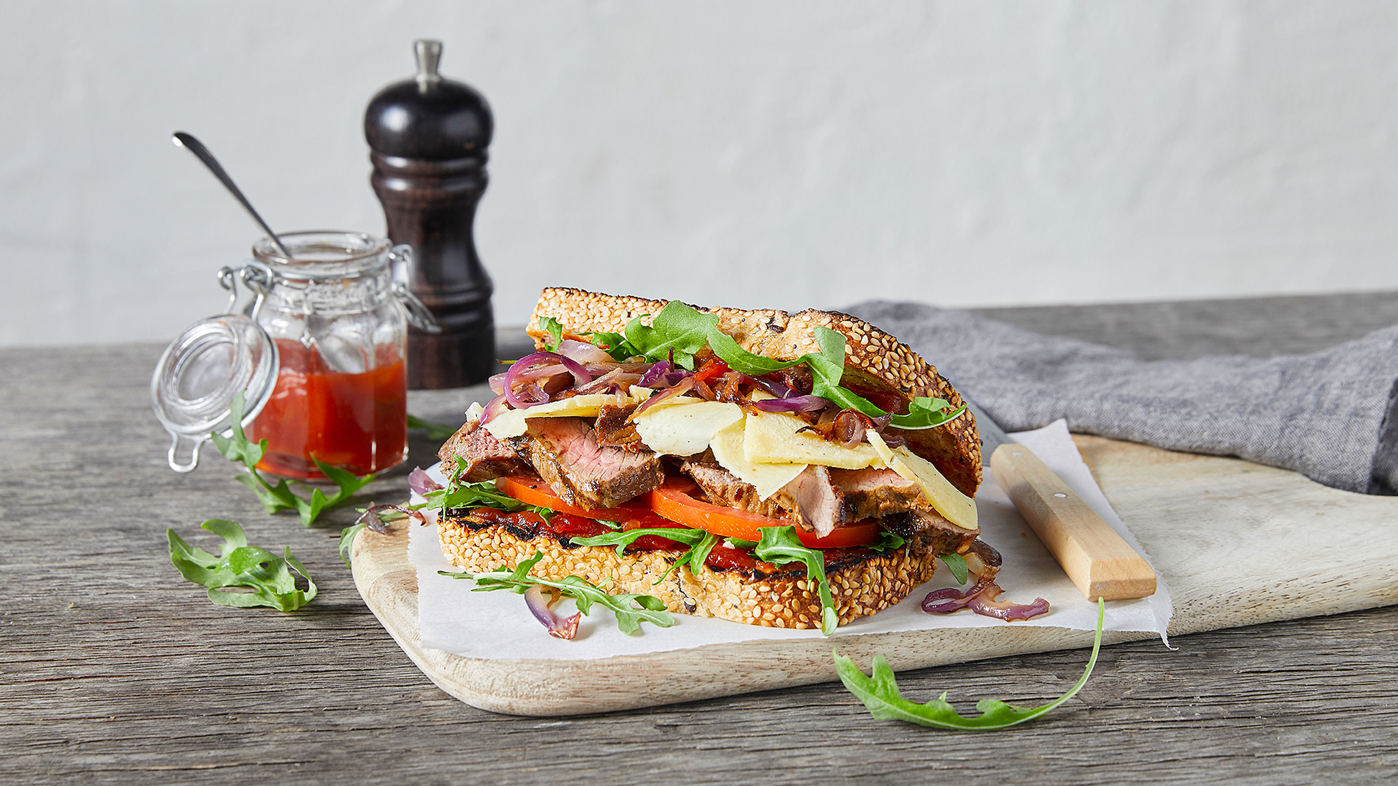 Centr's classic bbq steak sandwich sits on a wooden board, ready for eating.
