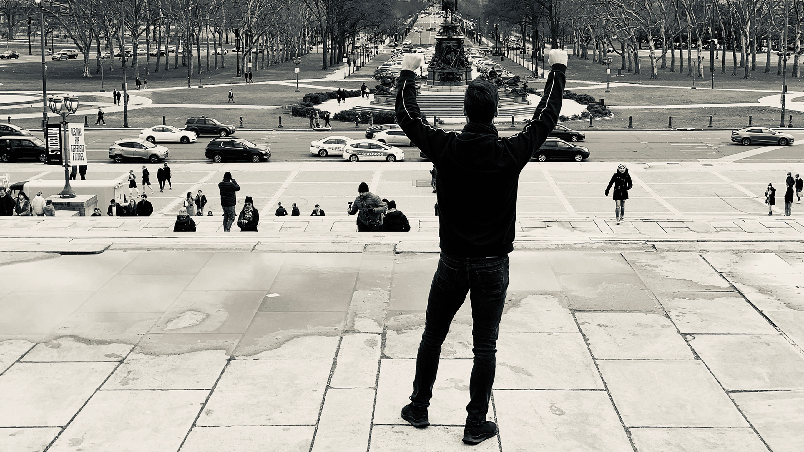 Centr member Robert stands at the top of a staircase with his hands raised in victory.