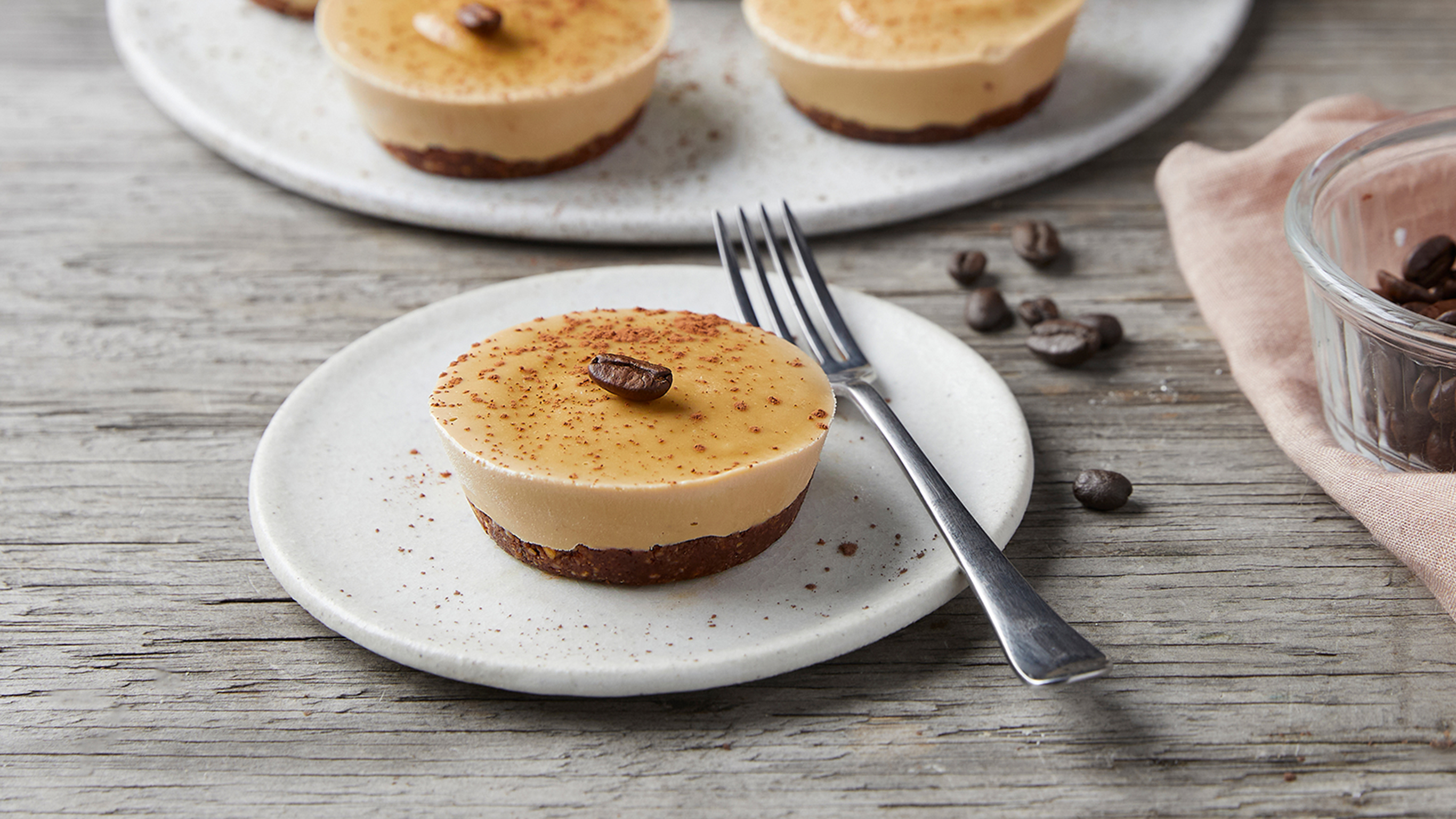 A ssingle Choc Espresso Cashew Cheesecake sits on a plate with a silver fork on the side, ready to eat.