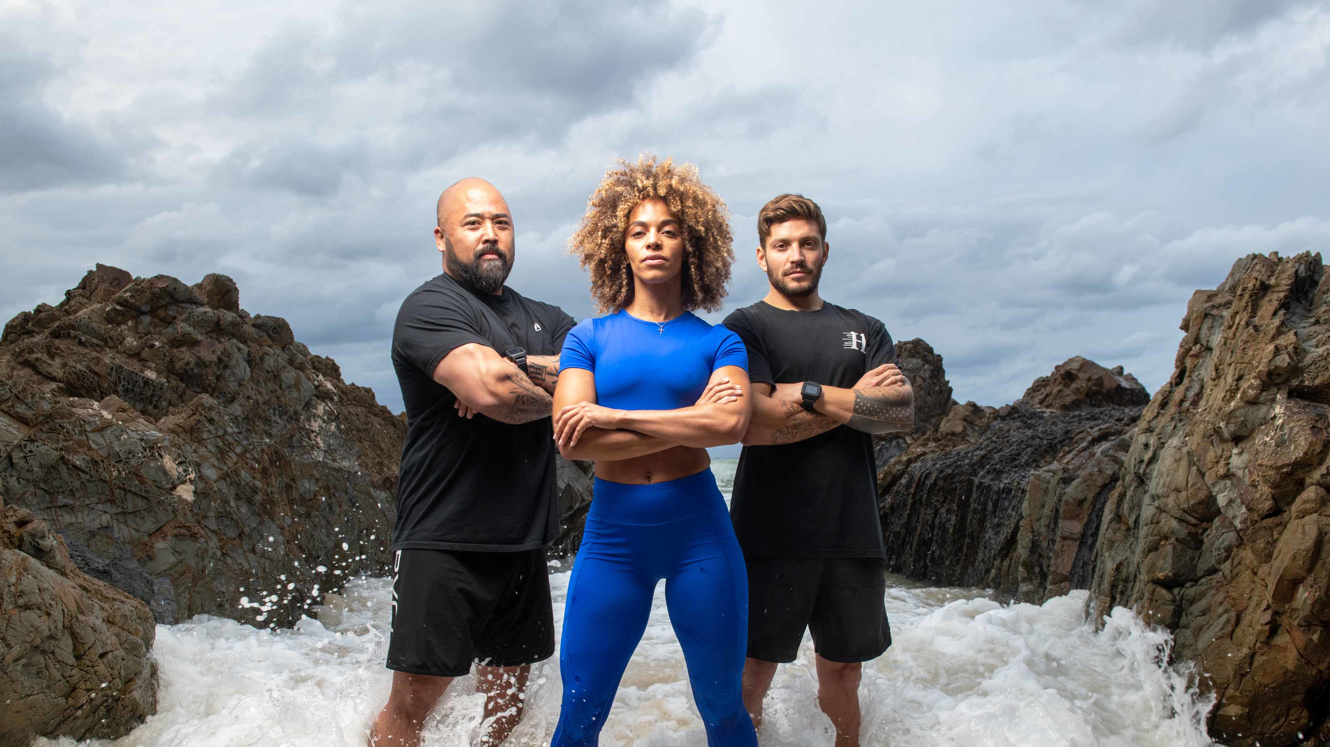 Ashley Joi, Luke Zocchi and Da Rulk stand in the ocean.