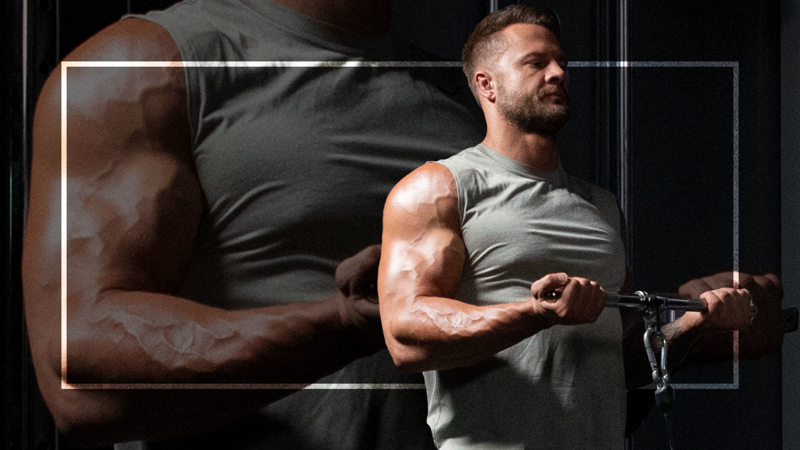 Centr trainer Bobby Holland Hanton., wearing a grey gym top,  performs a bicep curl with a straight bar cable.