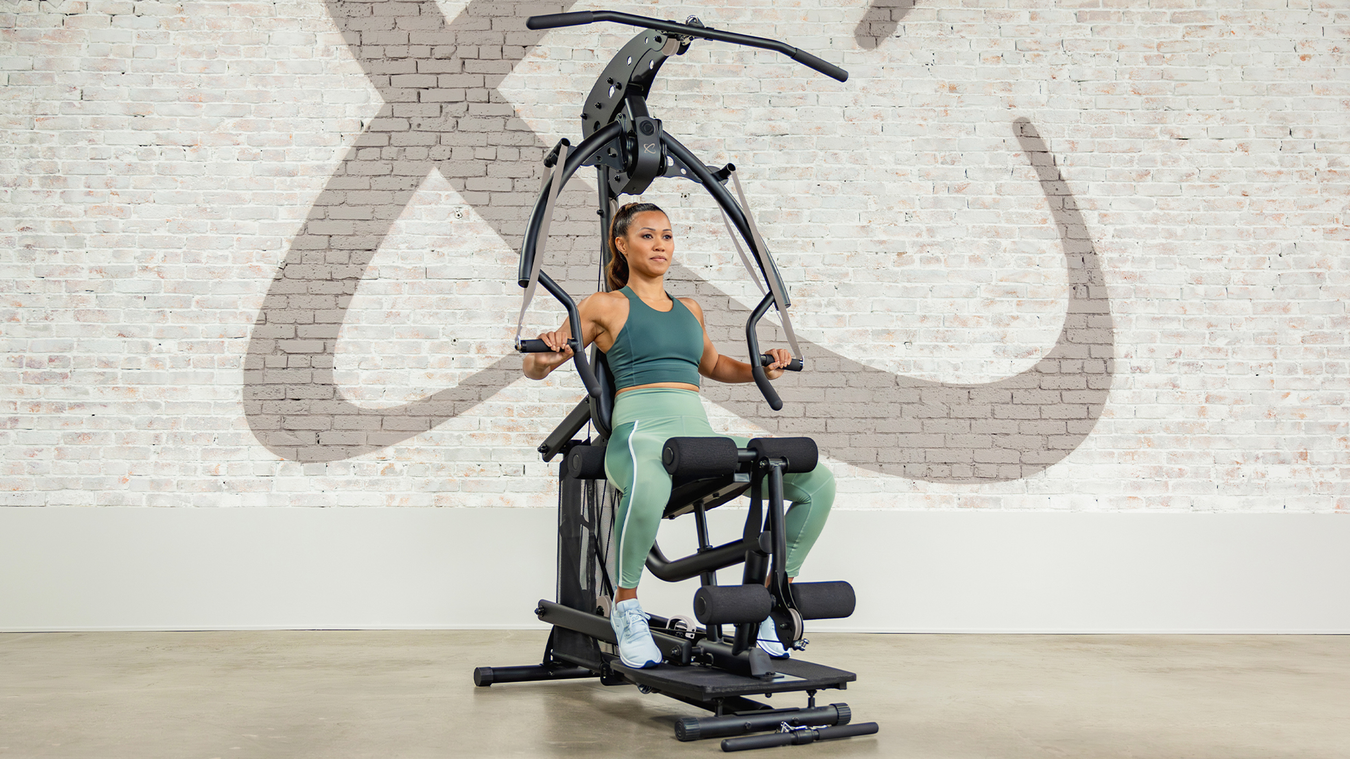 Centr trainers Ingrid Clay and Luke Zocchi perform an alternating bicep curl and a decline chest fly using the Centr 1 cable machine, as part of the Centr 1 Strong program.