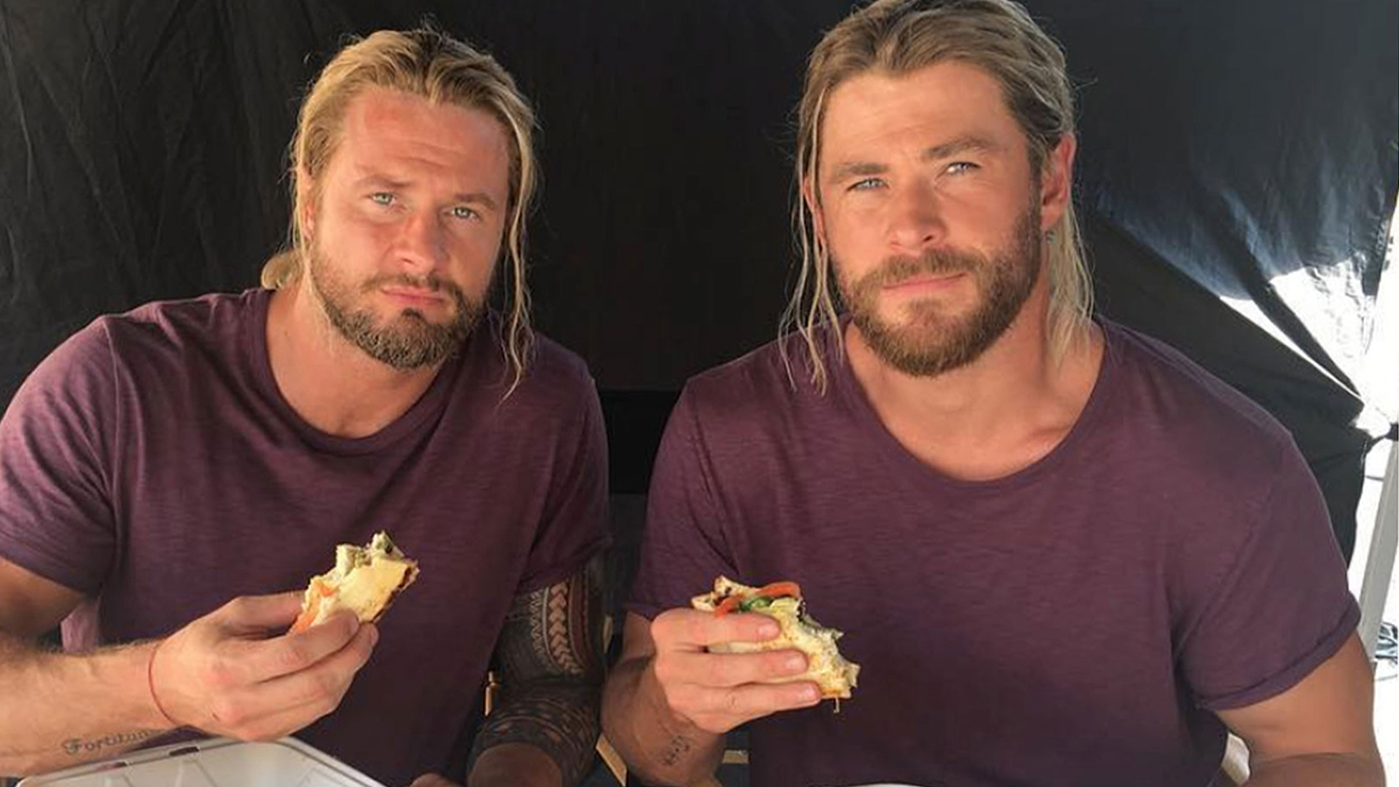 Chris Hemsworth and his stunt double eating sandwiches while wearing matching 'Thor' wigs.