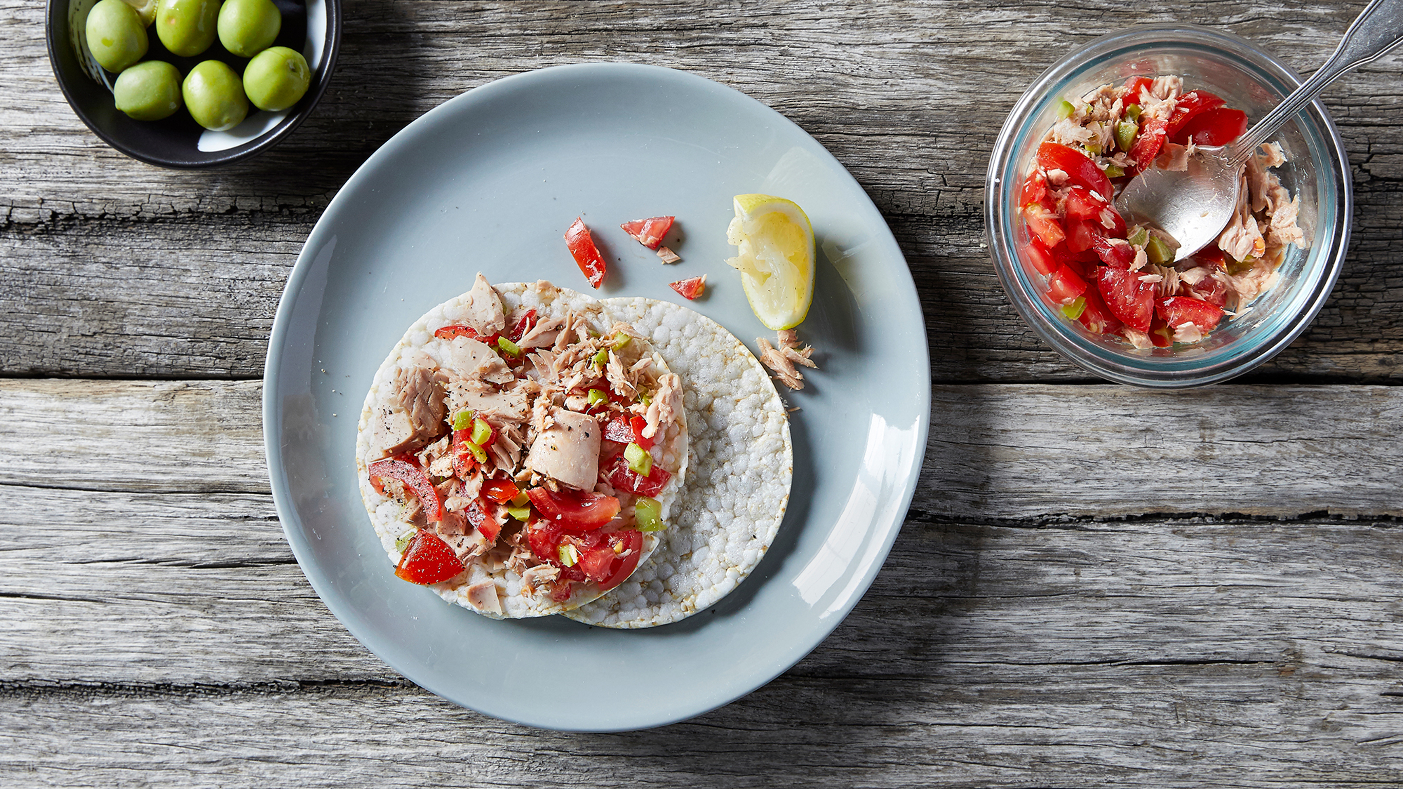 A plate of rice cakes covered with tuna and tomato.