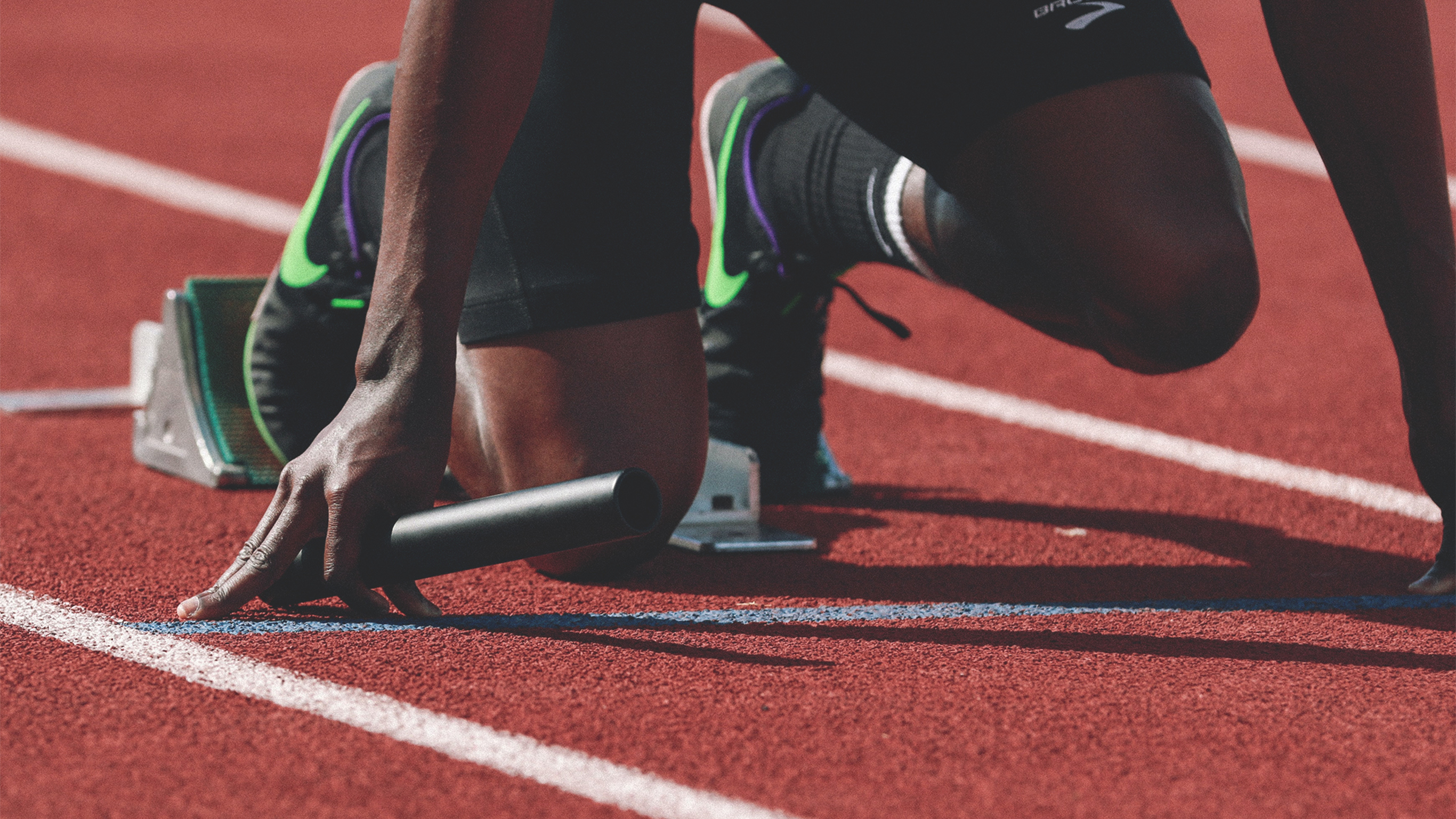 A close-up shot of a relay runner’s feet on the starting block.