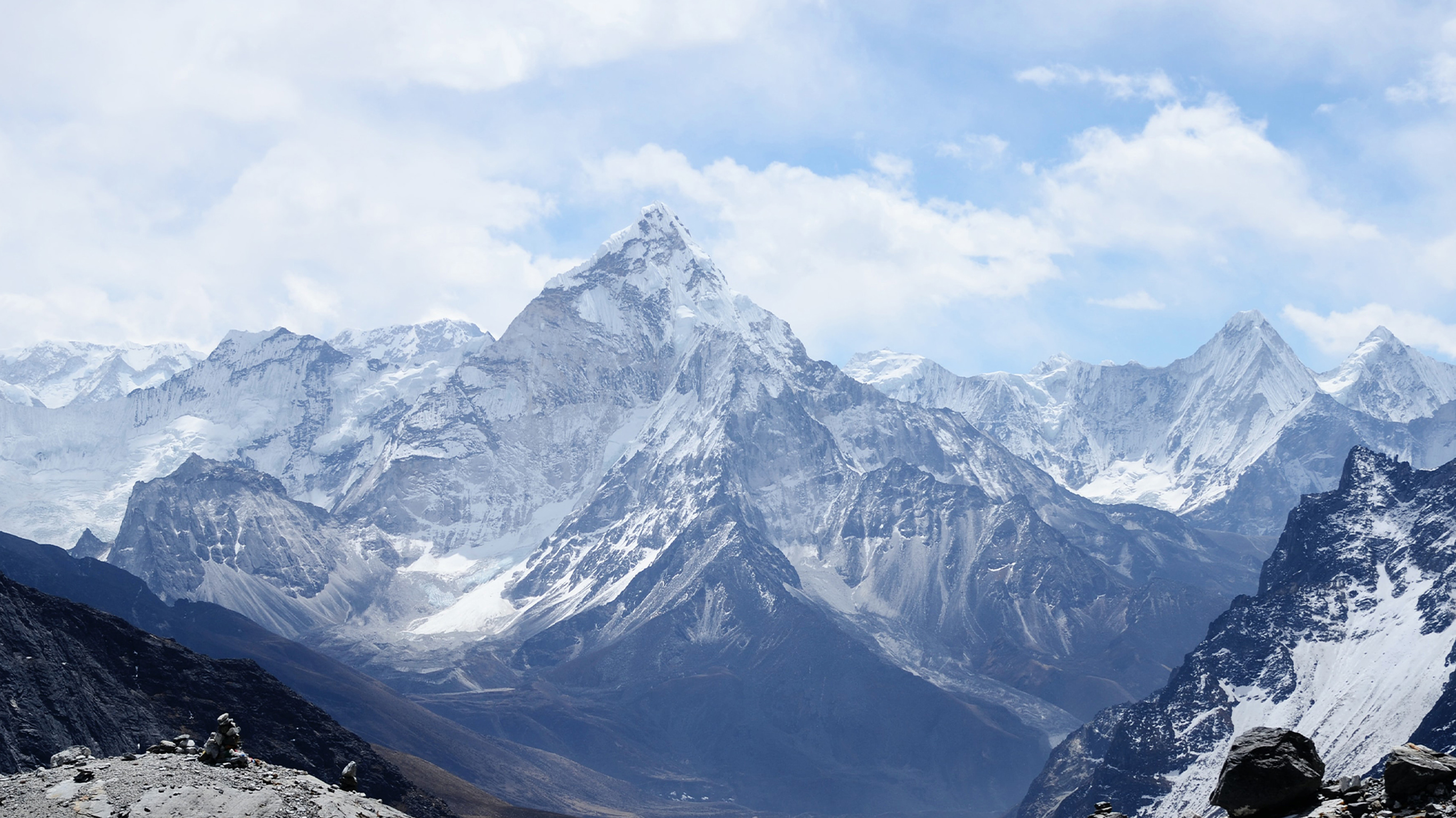 A blue and grey mountain range with snow-dusted peaks.