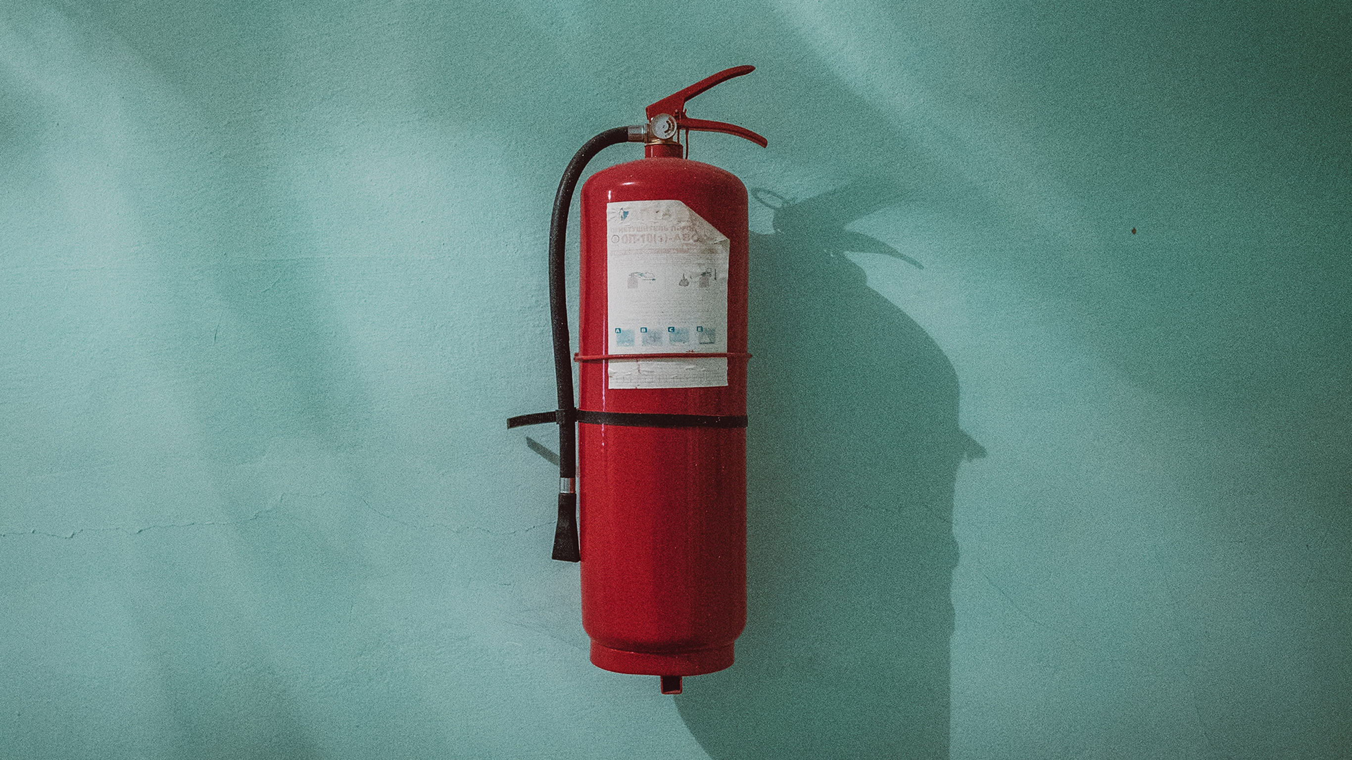 A red fire hydrant hanging on a blue wall.