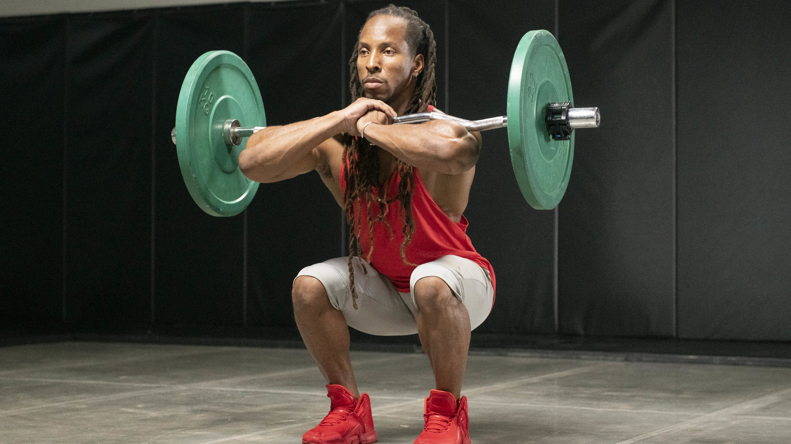 Bodybuilder Torre Washington performs a front squat with a loaded barbell to build muscle.