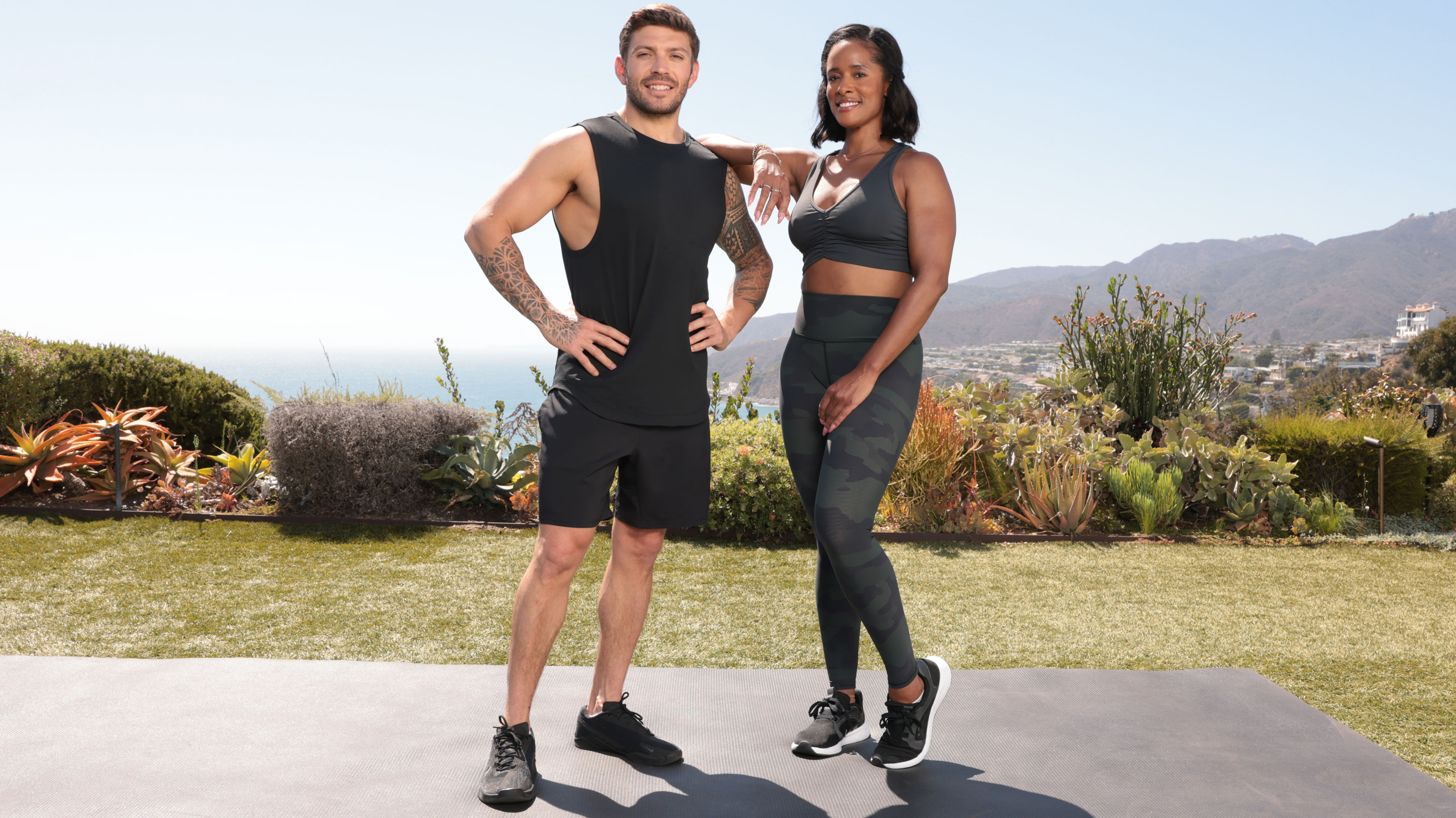 Centr HIIT HIRT strength trainers Luke Zocchi and Ingrid Clay pose together while standing on a workout mat.