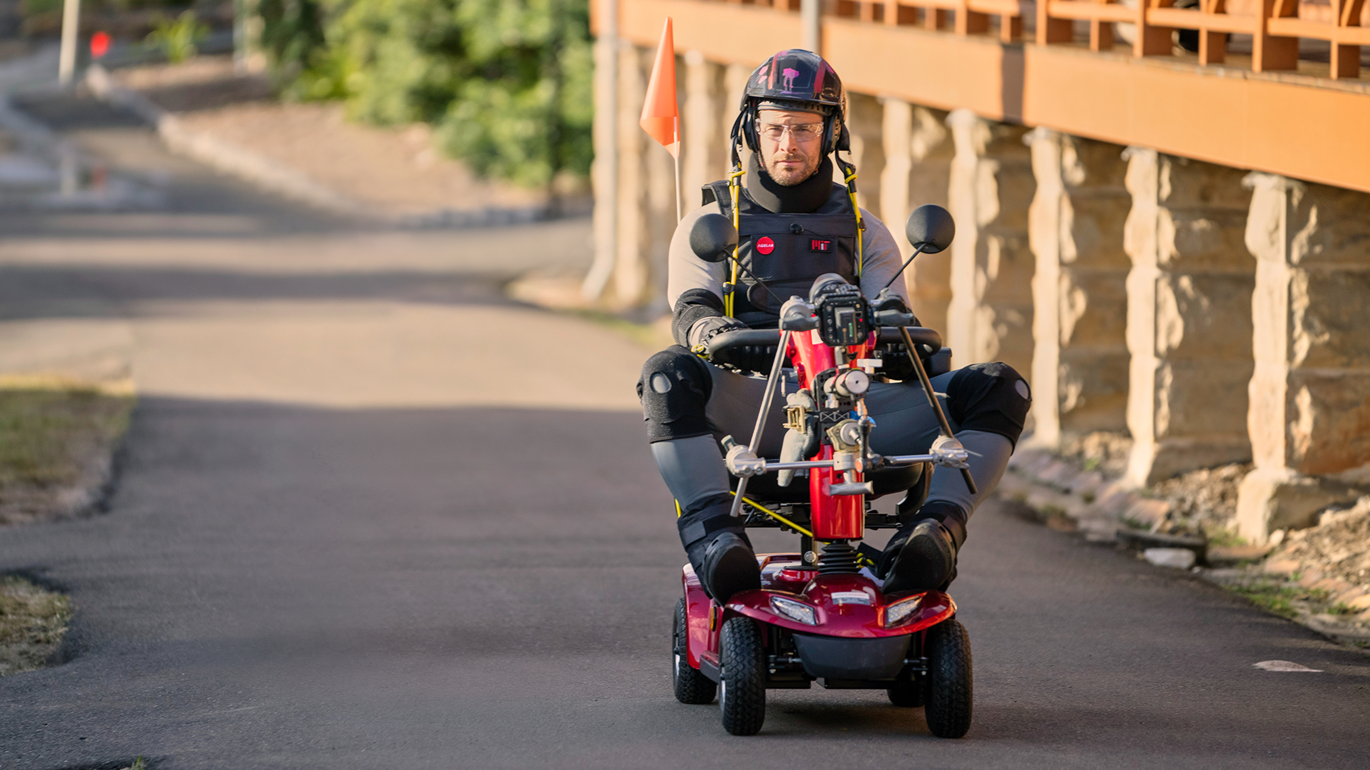 Centr founder Chris Hemsworth, wearing protective clothing and a helmet, rides a mobility scooter.
