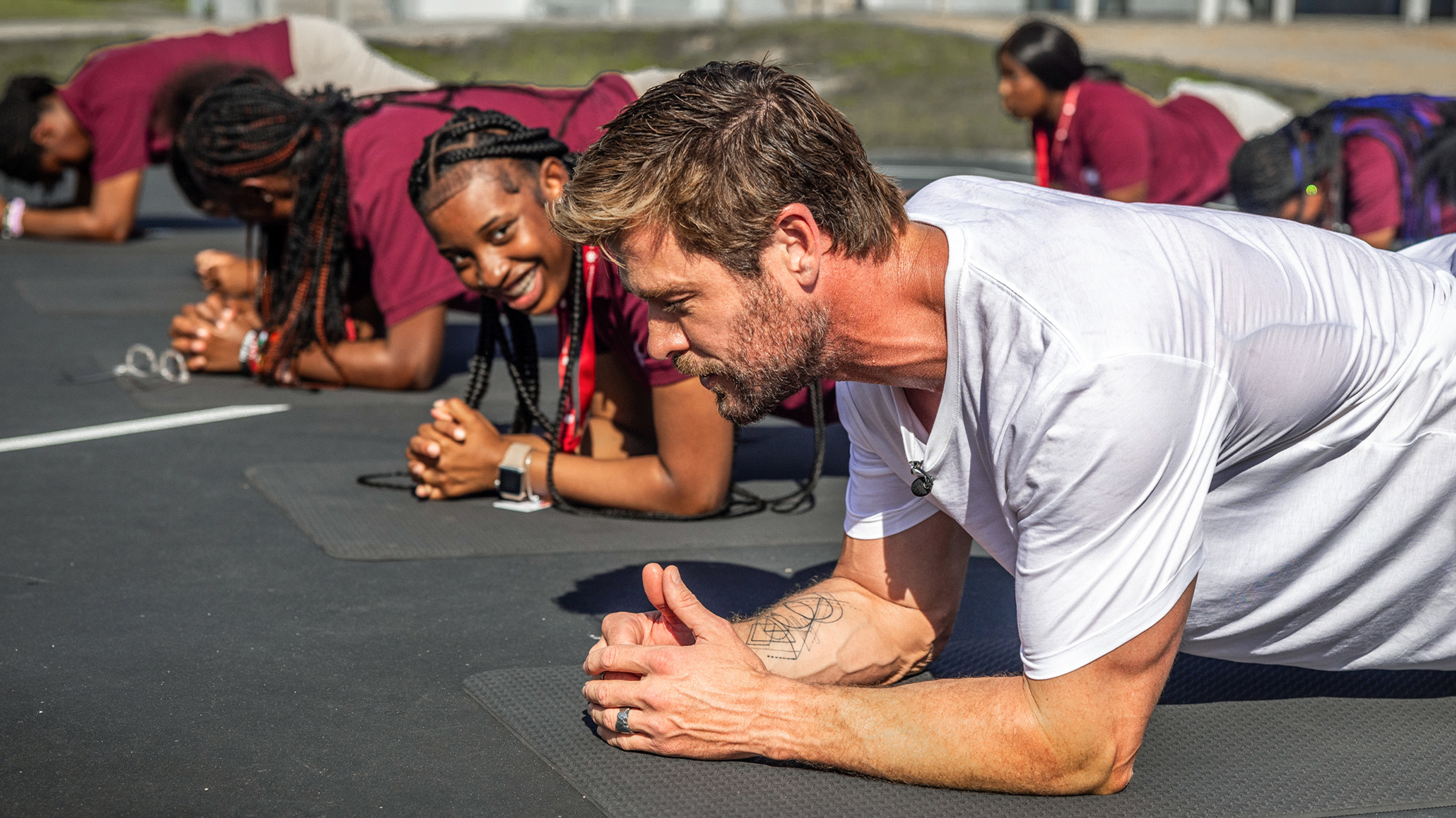 Centr founder Chris Hemsworth performs a plank with some students from the SEED School Miami.