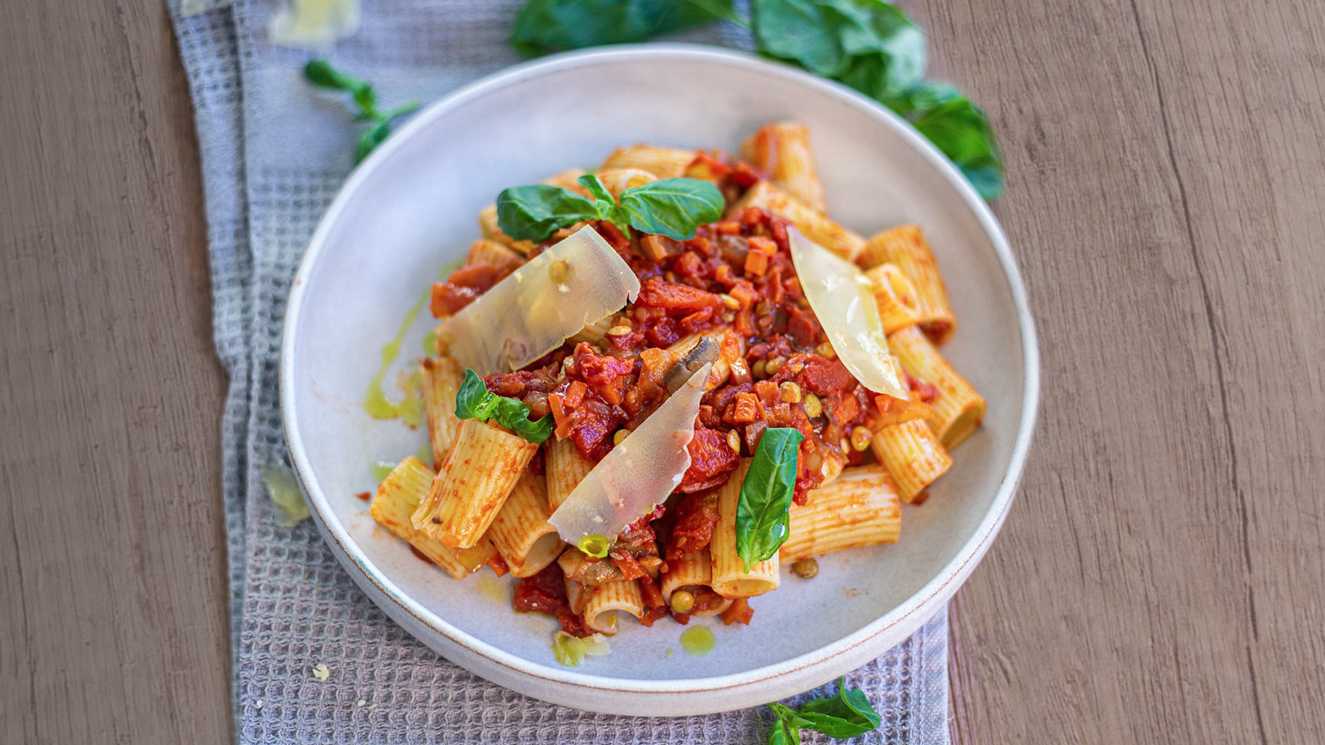A round plate of Centr's Spicy Vegan Ragu sits on a grey waffle tea towel, ready for eating.