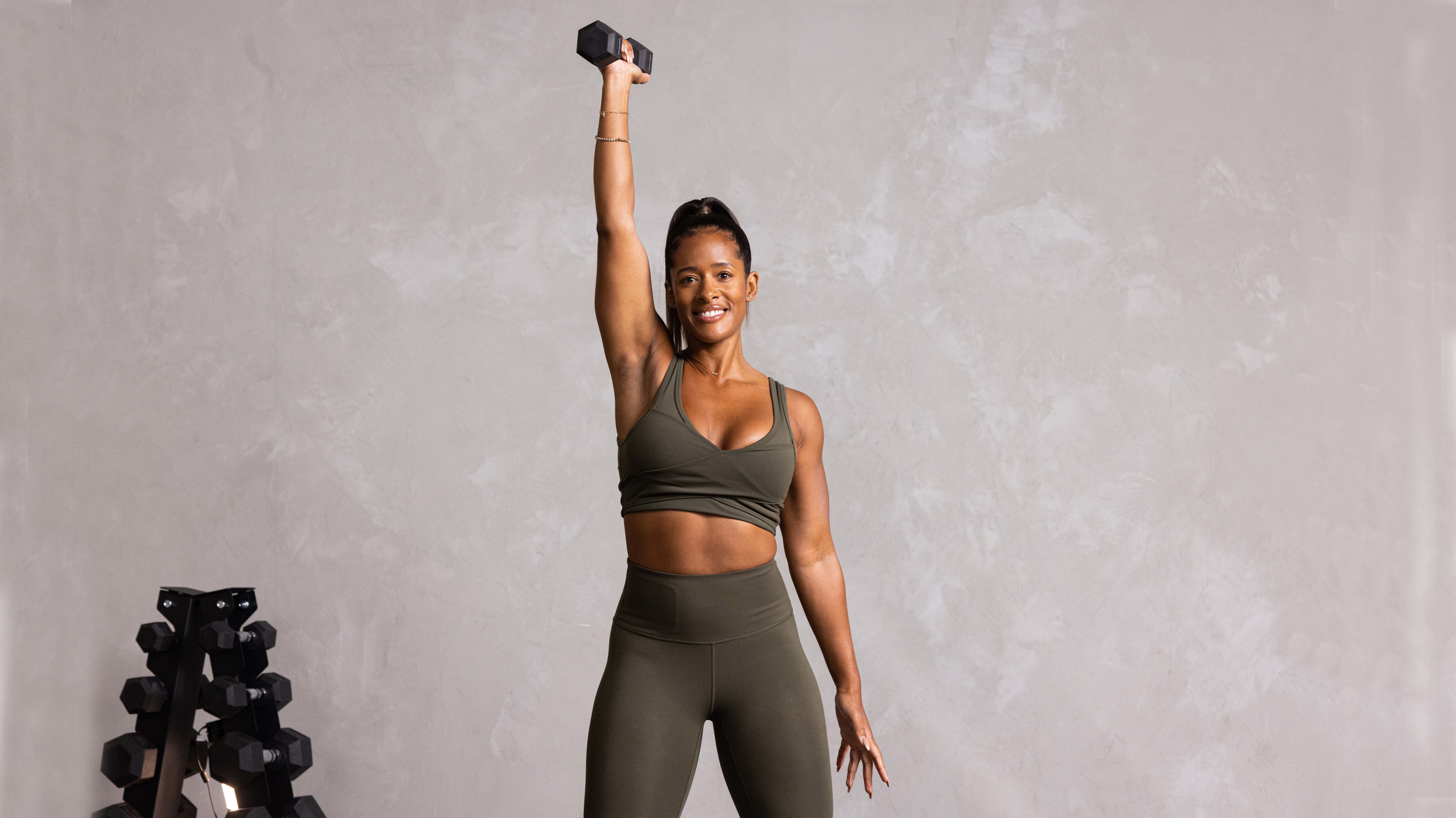 Ingrid Clay performs an overhead press with a heavy dumbbell.