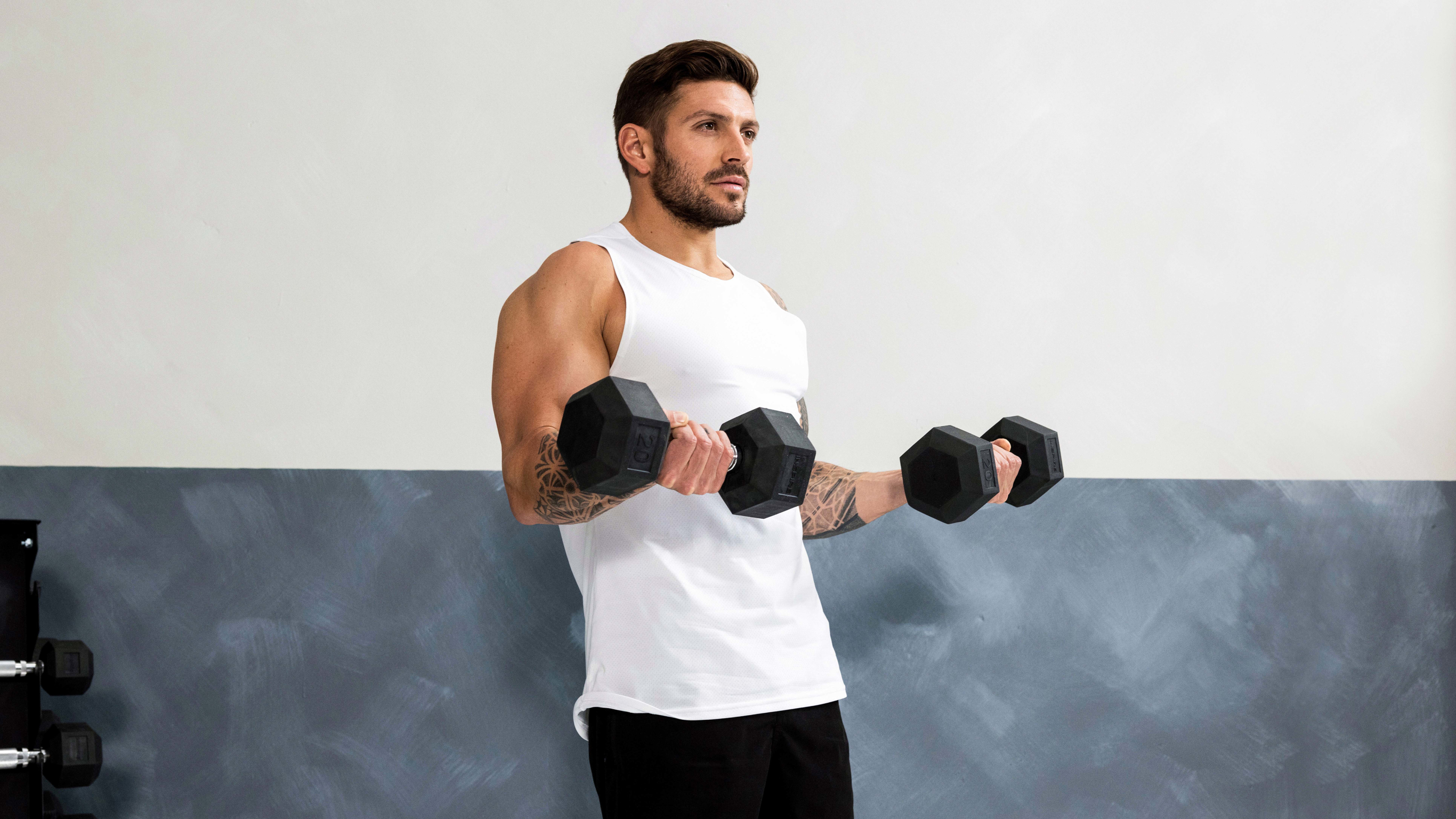 Luke Zocchi performs bicep curls with large dumbbells.