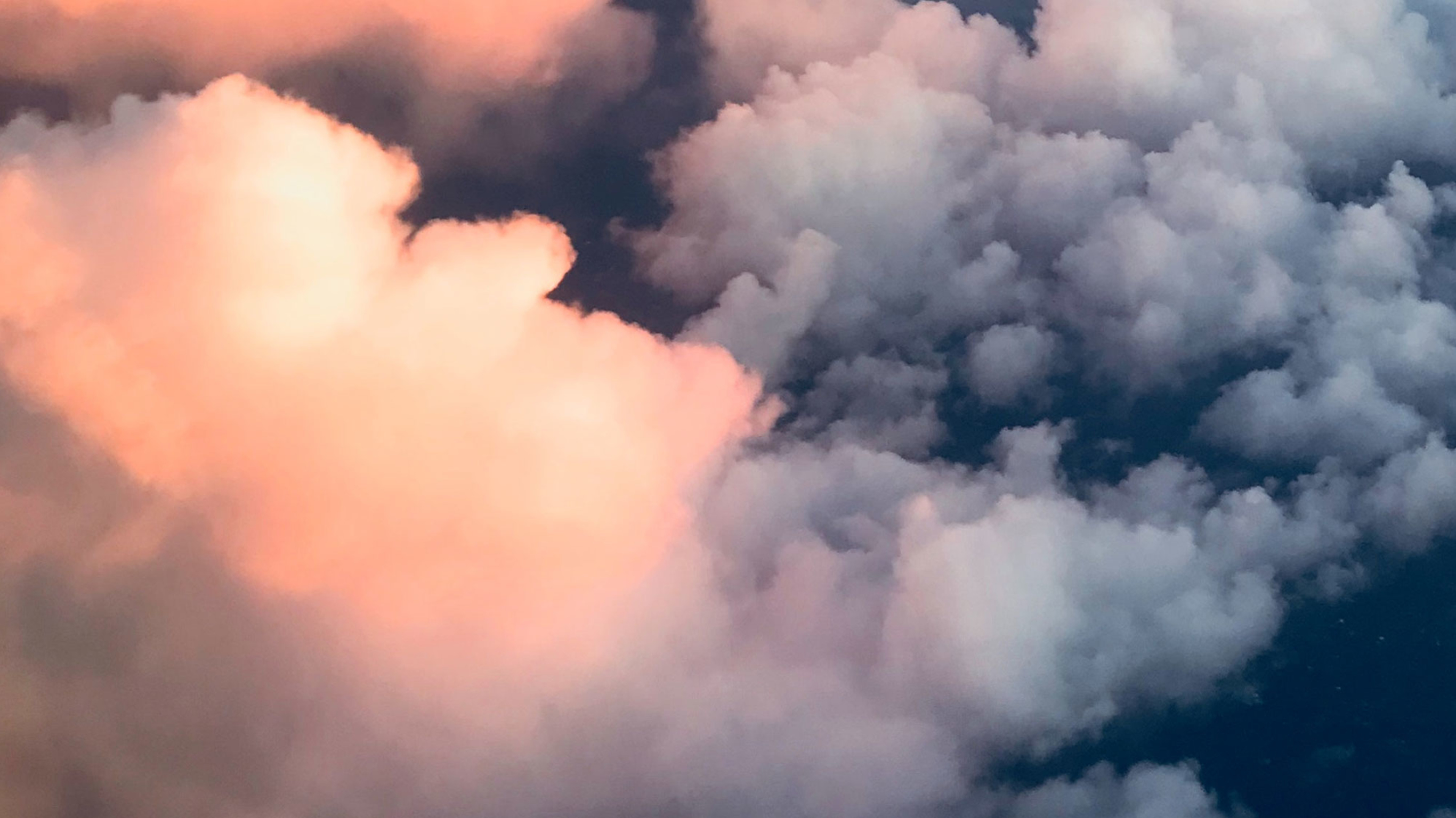 Clouds roll across the evening sky, seen from above.