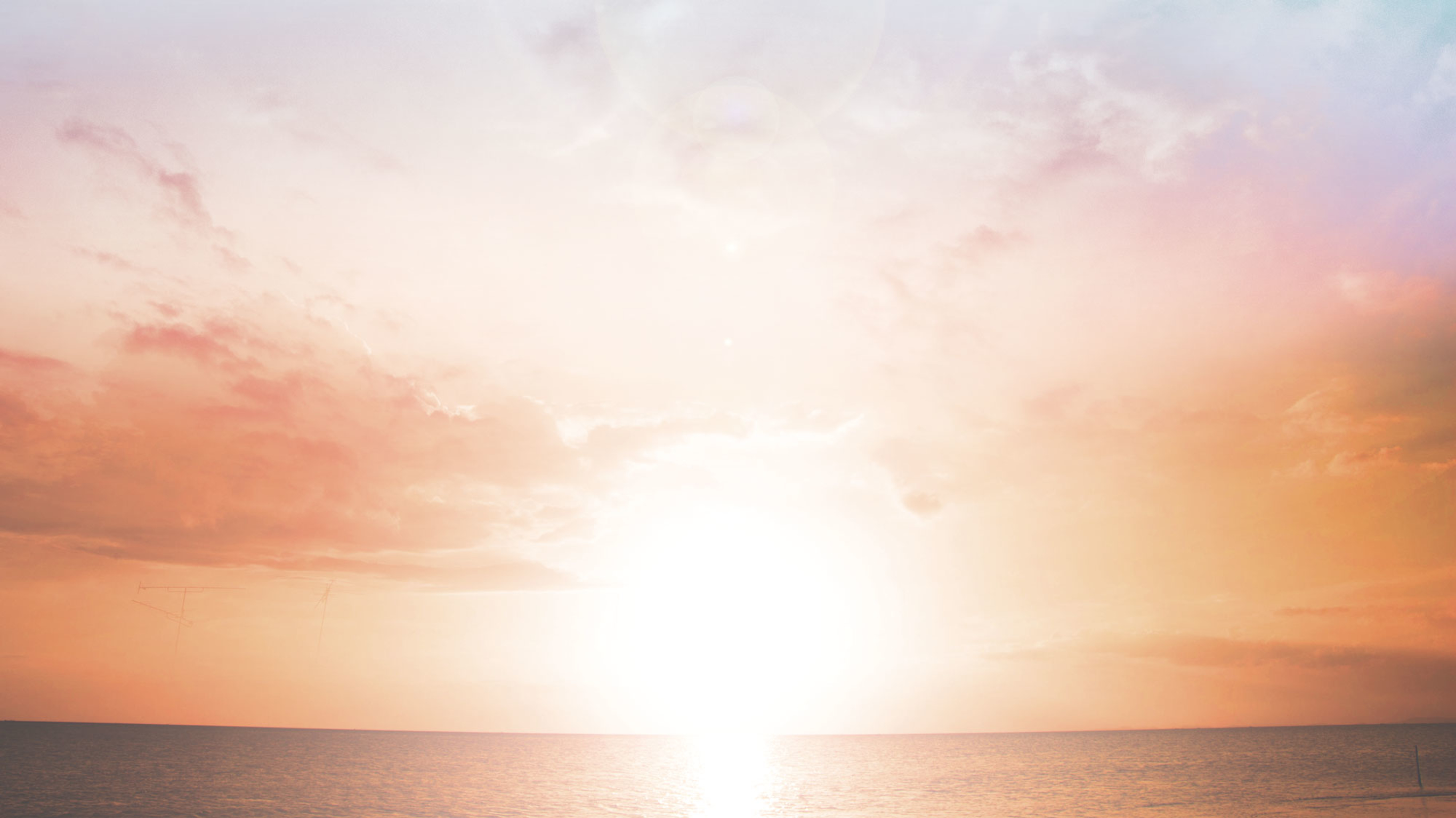 A brilliant red sun sits on the ocean's horizon.