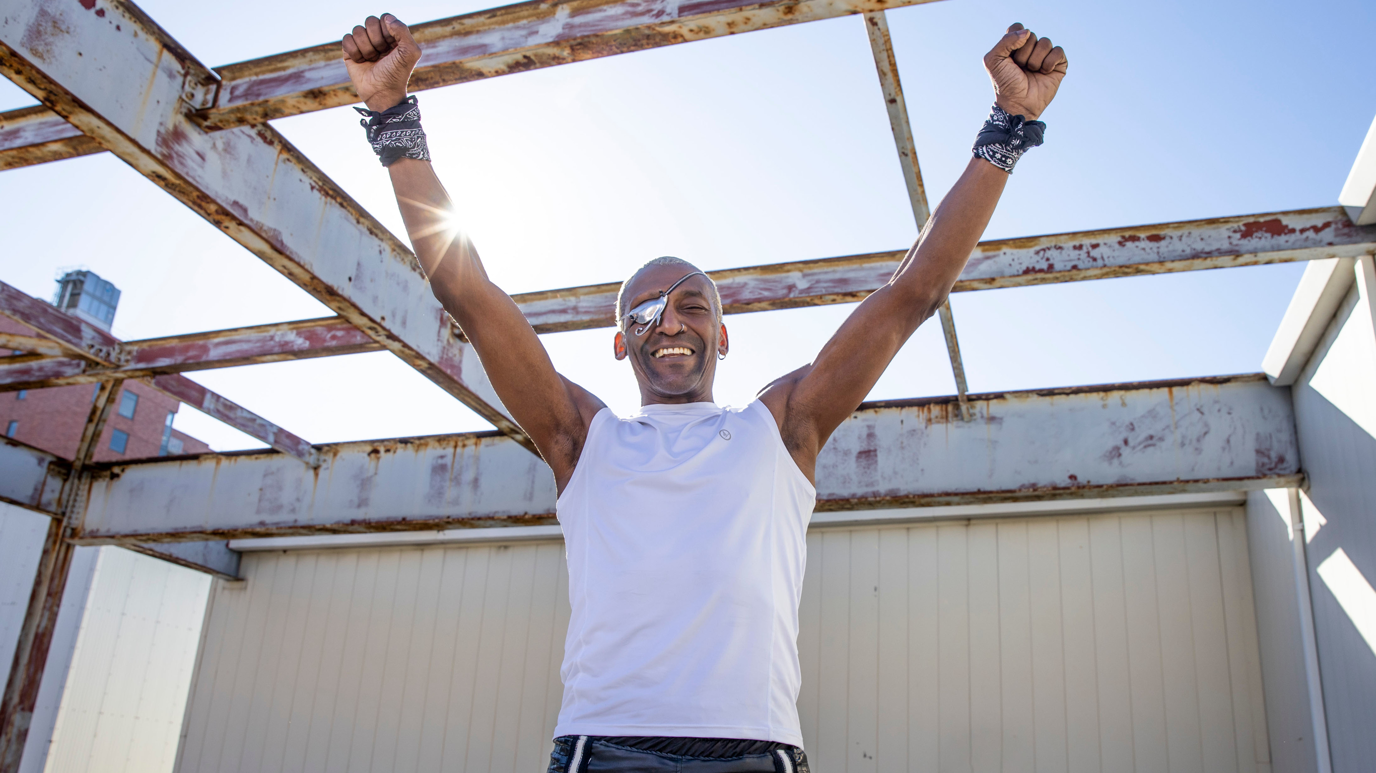 Centr Boxing trainer and Meditation narrator Michael Olajide Jr. raises his arms overhead and smiles broadly.