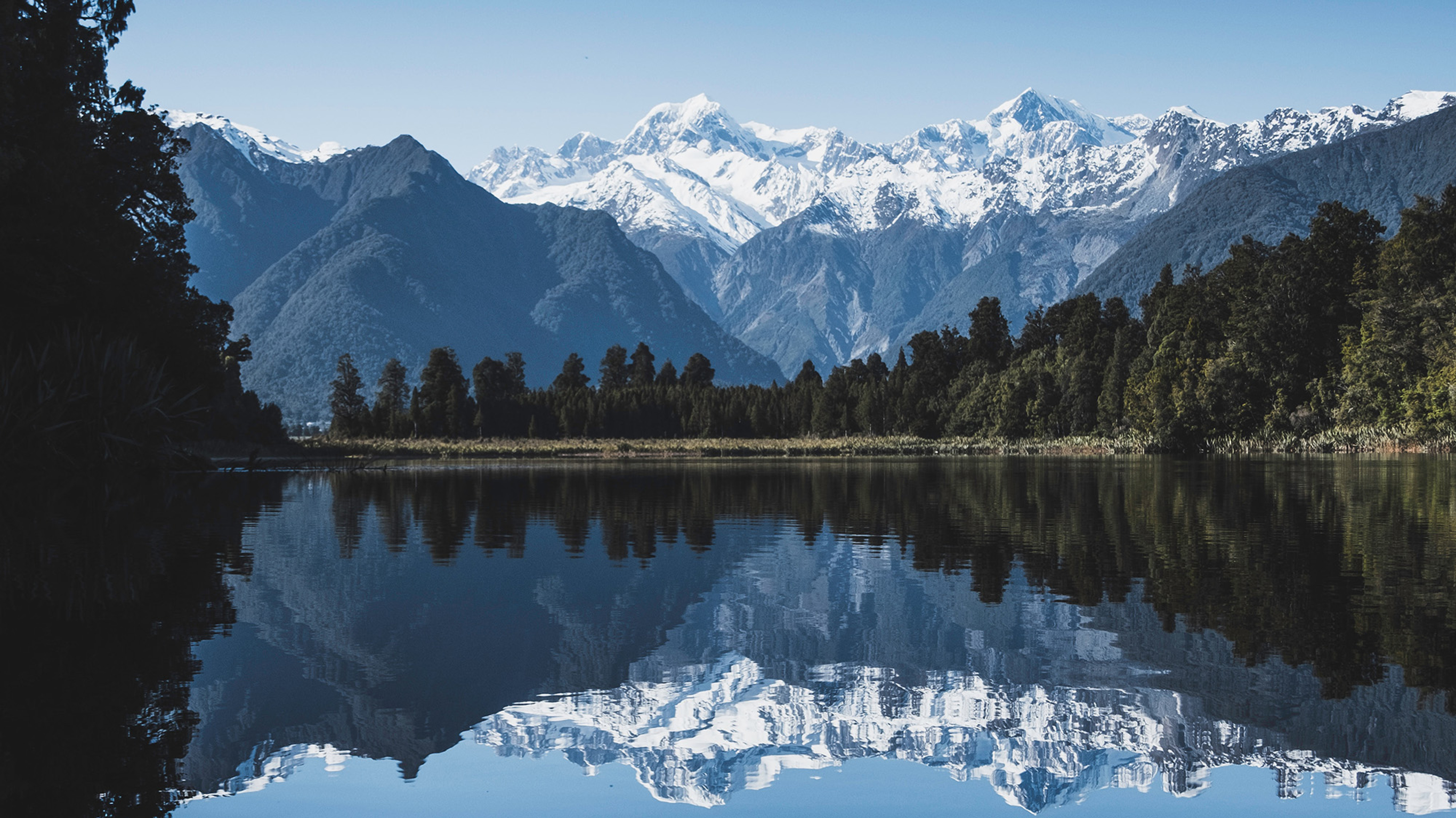 A snow-capped mountain vista, reflected in a calm lake.