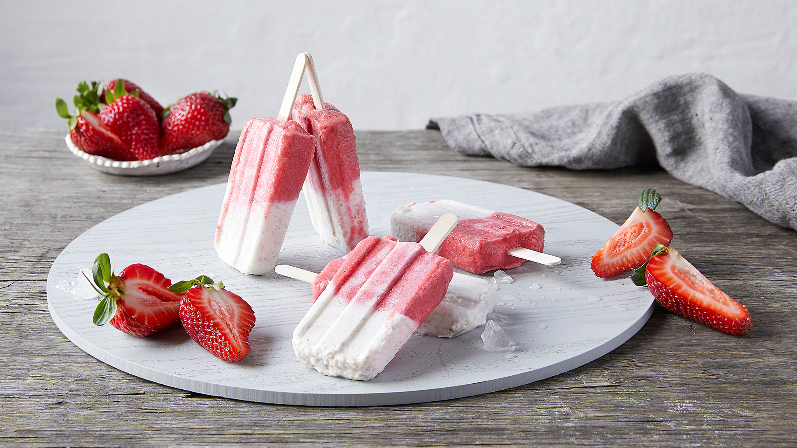 Several Coconut, Chia & Strawberry Ice Creams, from the Centr meal plan, sit on a table alongside some fresh strawberries.