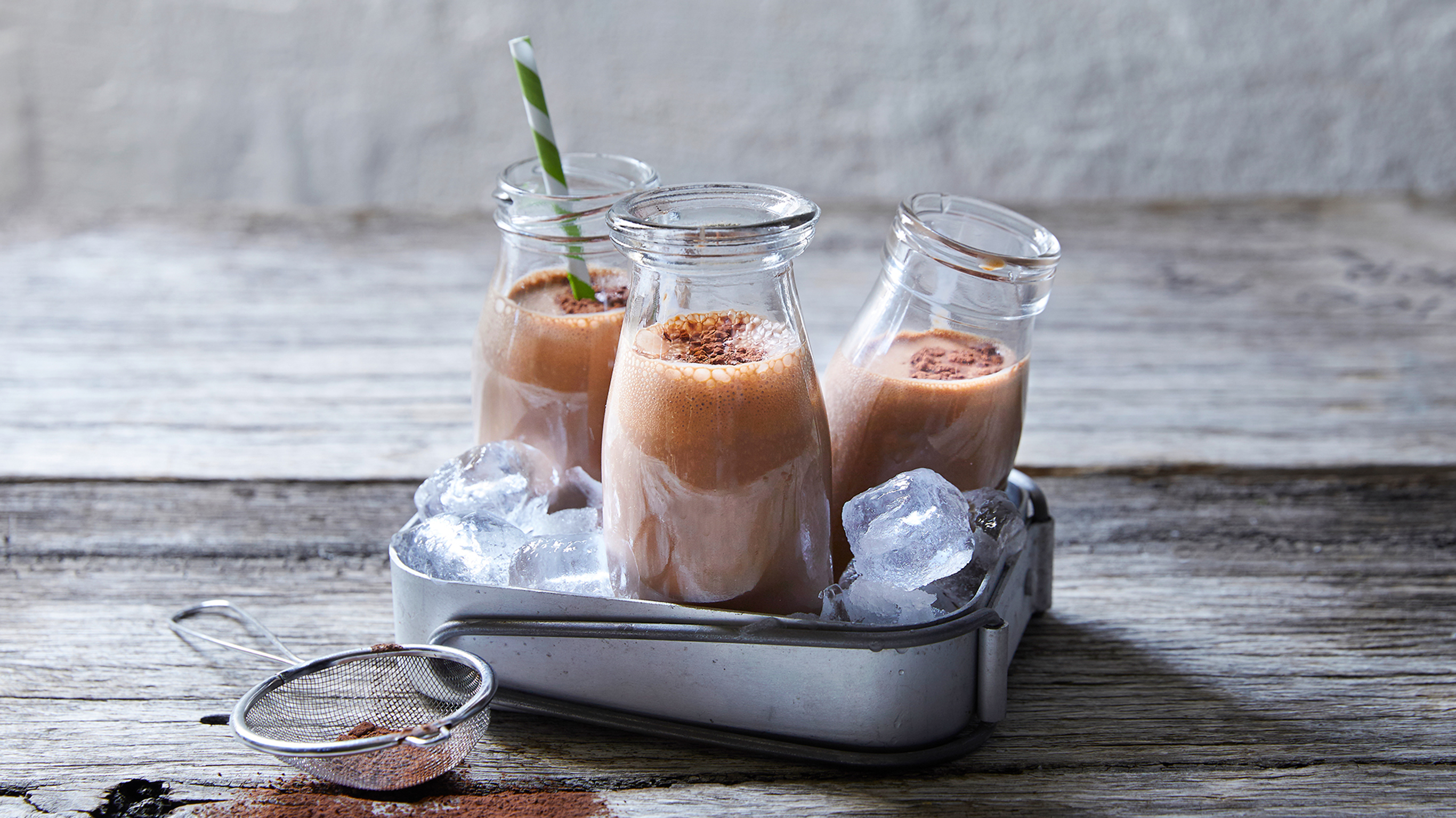 Three glasses of Chocolate Espresso Snack Smoothie, from the Centr meal plan, sit on a table in a tray of ice.