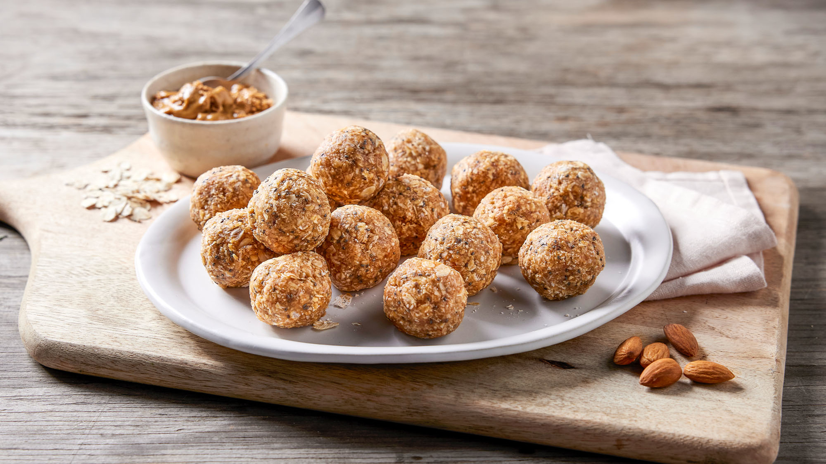 A plate of recovery almond & banana bites sits on a wooden board.