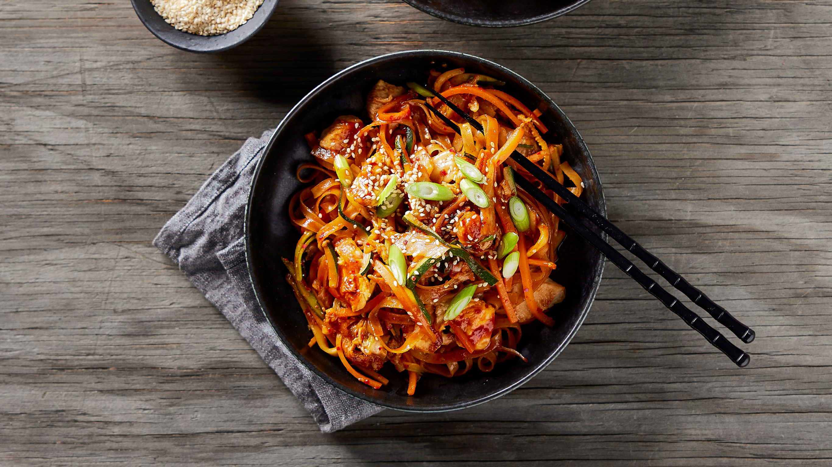 A wok of Dan's kimchi fried rice with chicken and veggies sits on a wooden table.