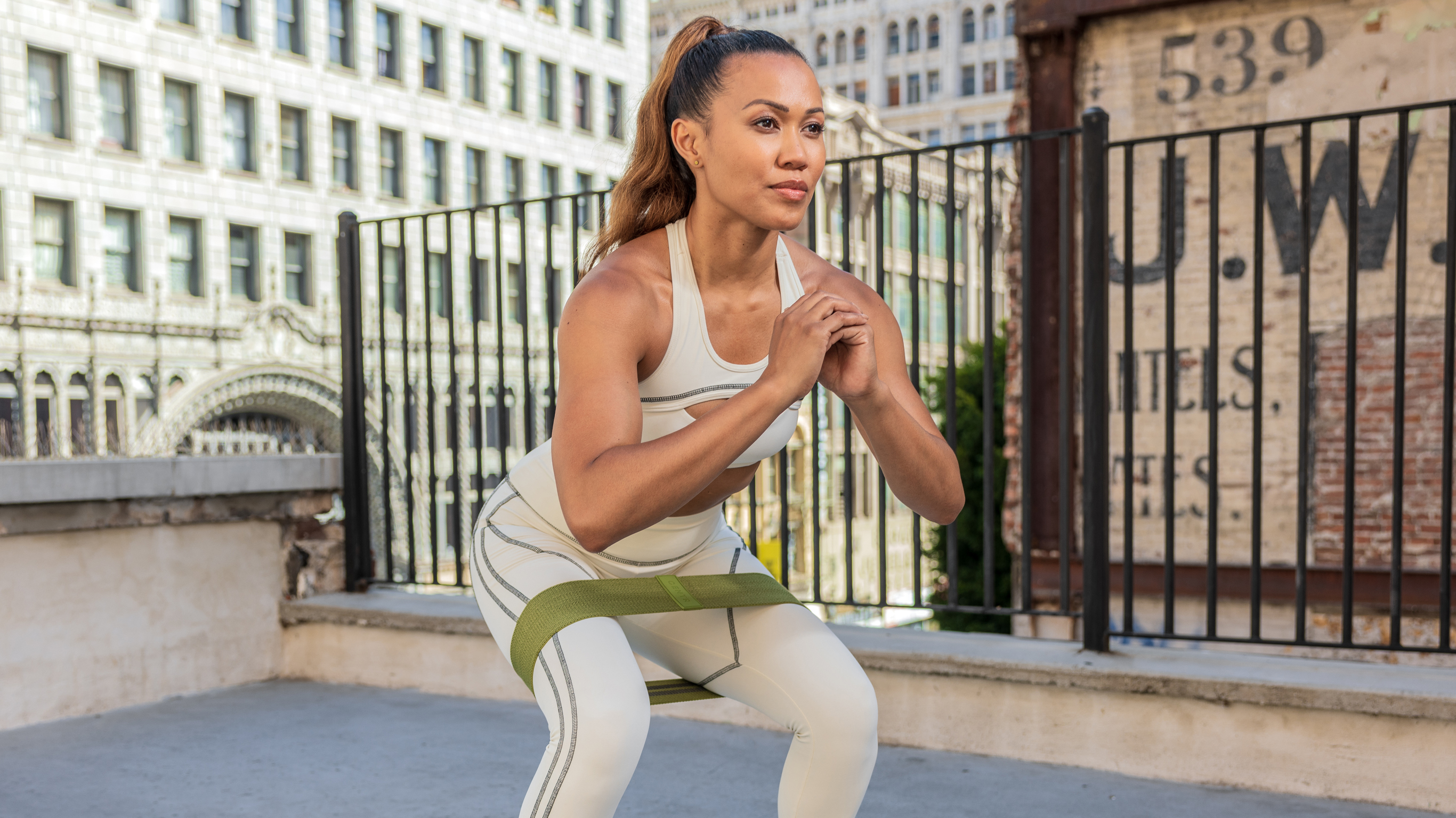 Centr Trainer Maricris Lapaix performs a banded squat with a fabric band from the Centr Workout Kit.