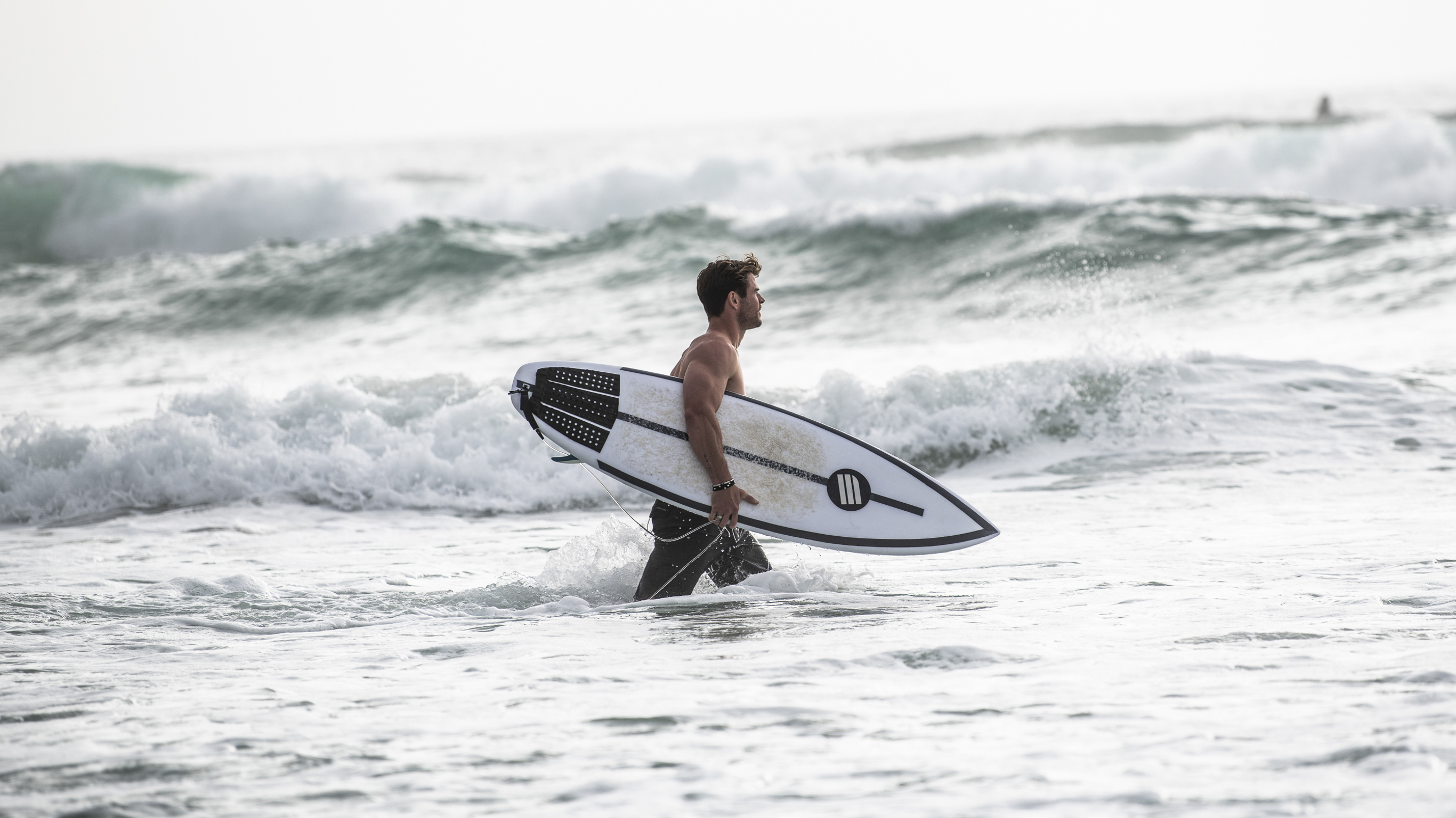 Chris Hemsworth with a surfboard in the waves at Byron Bay.