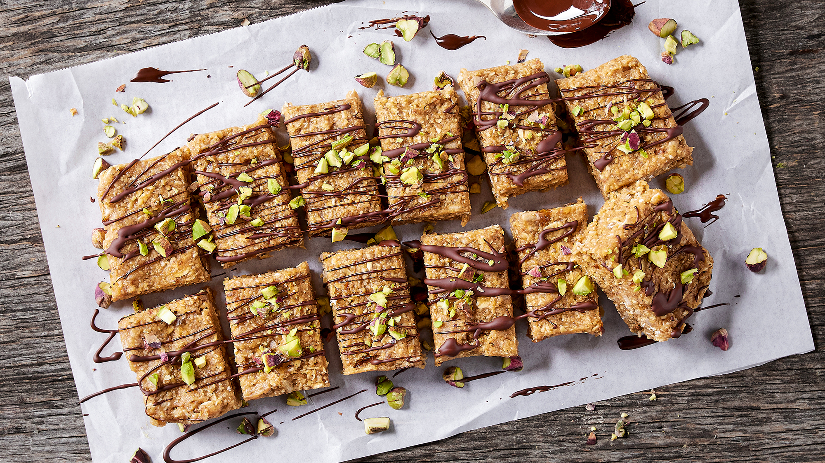 Centr's Choc Pistachio Cookie Dough Bar sliced into many pieces and drizzled with chocolate.