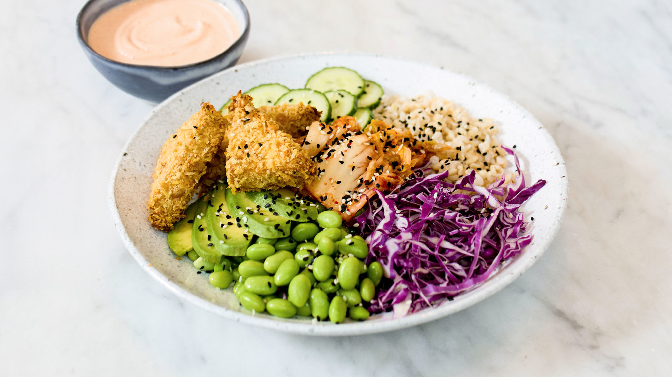 A serve of air fryer tofu nugget salad bowl rests on a marble bench, ready for eating.