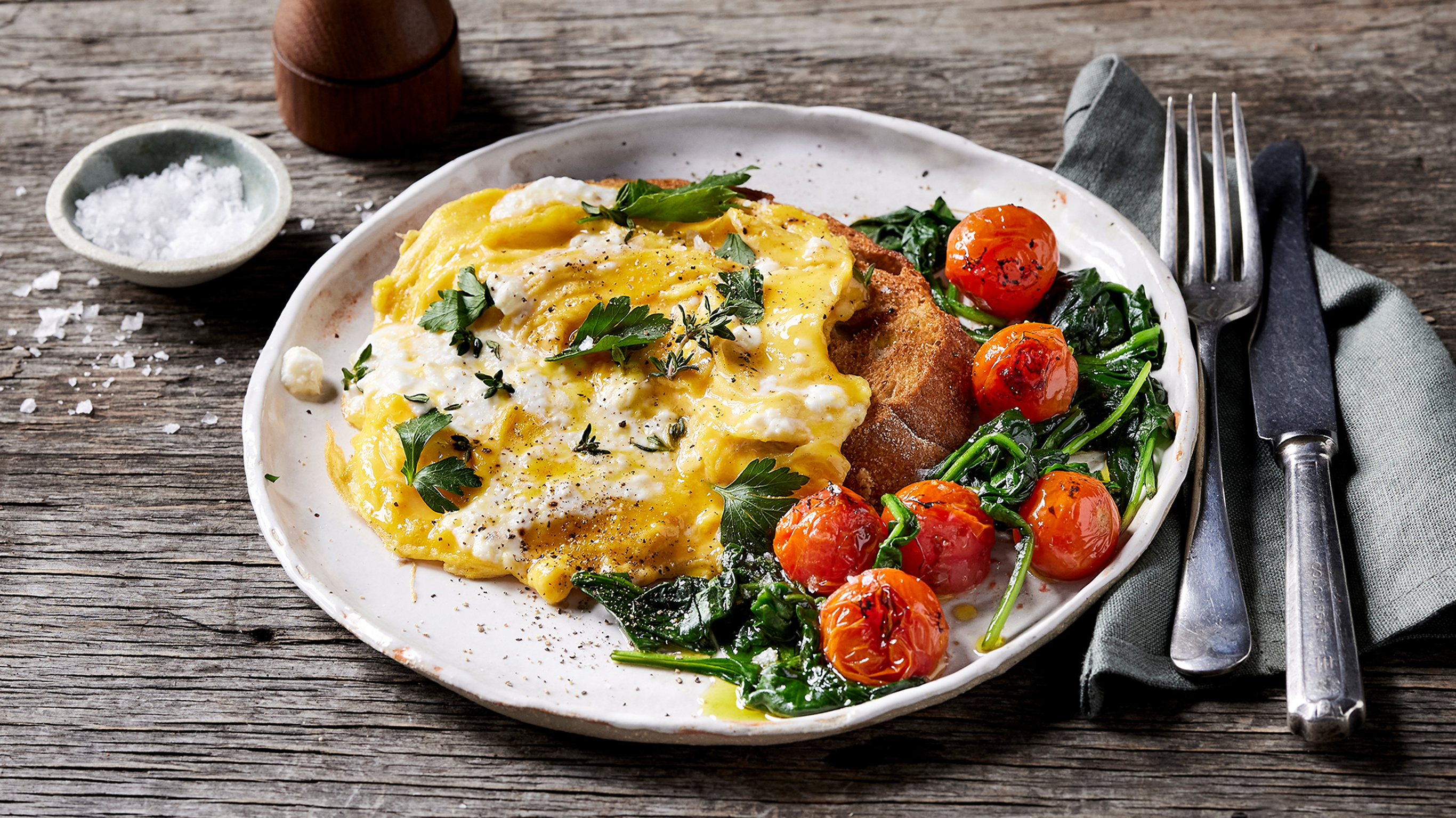 A plate of Centr's Cheesy Scramble with Spinach & Tomatoes is ready to eat.