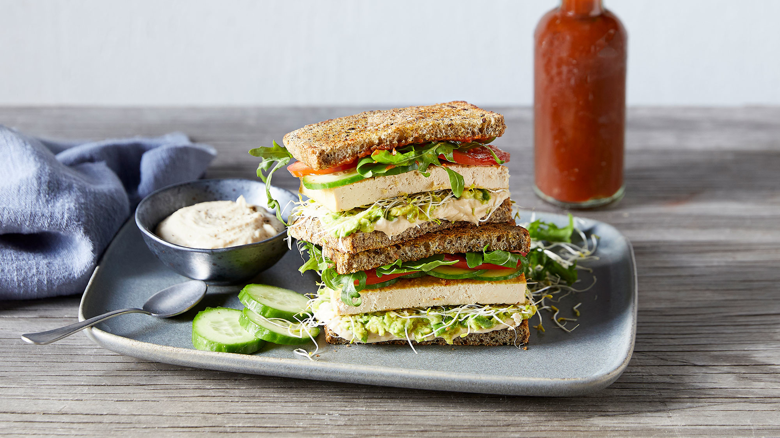 A tower of Centr's Ultimate Plant-based Sandwich sits on a plate, ready for eating.