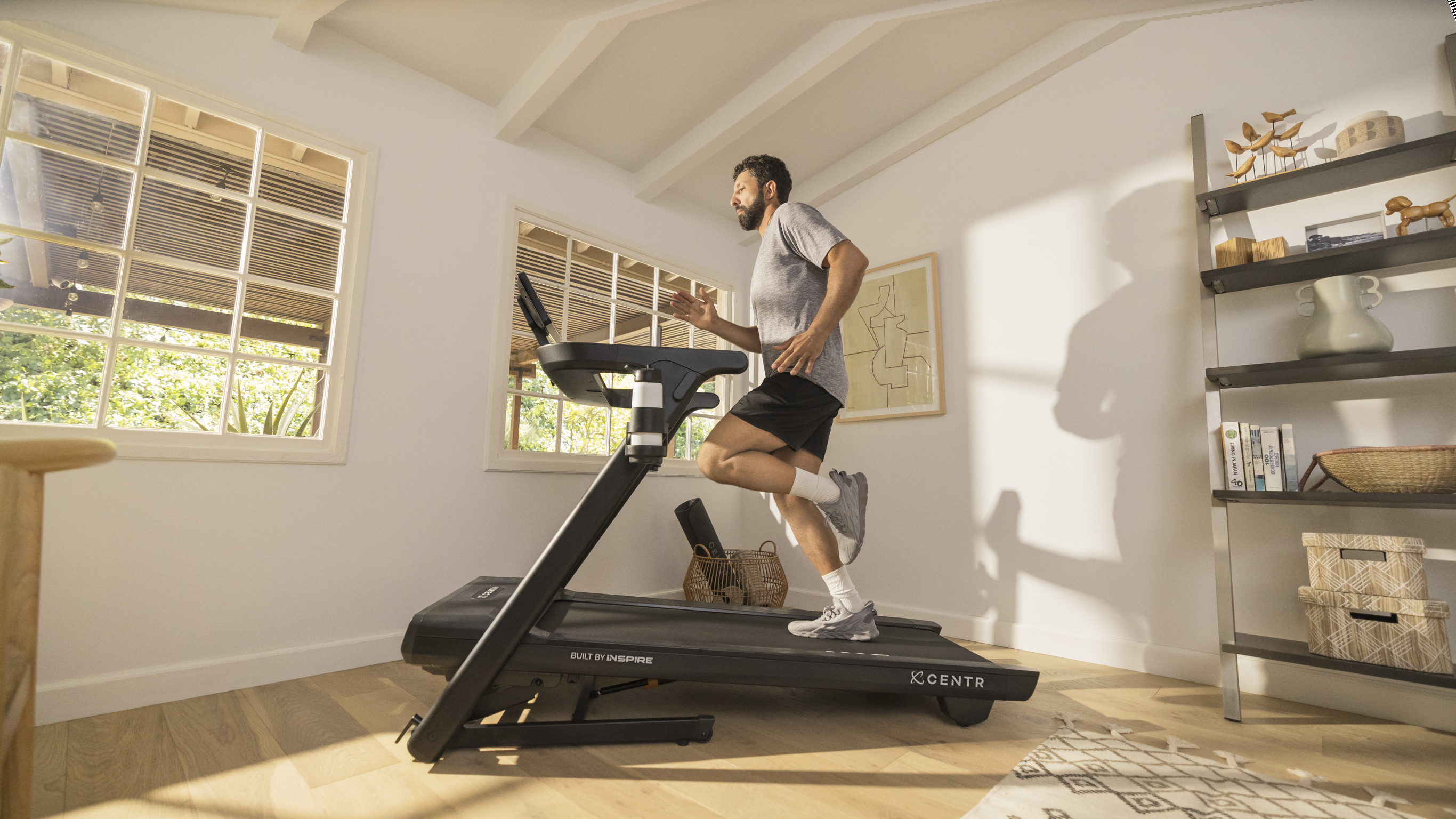 A Centr subscriber runs on his treadmill in a light-filled room in his house.