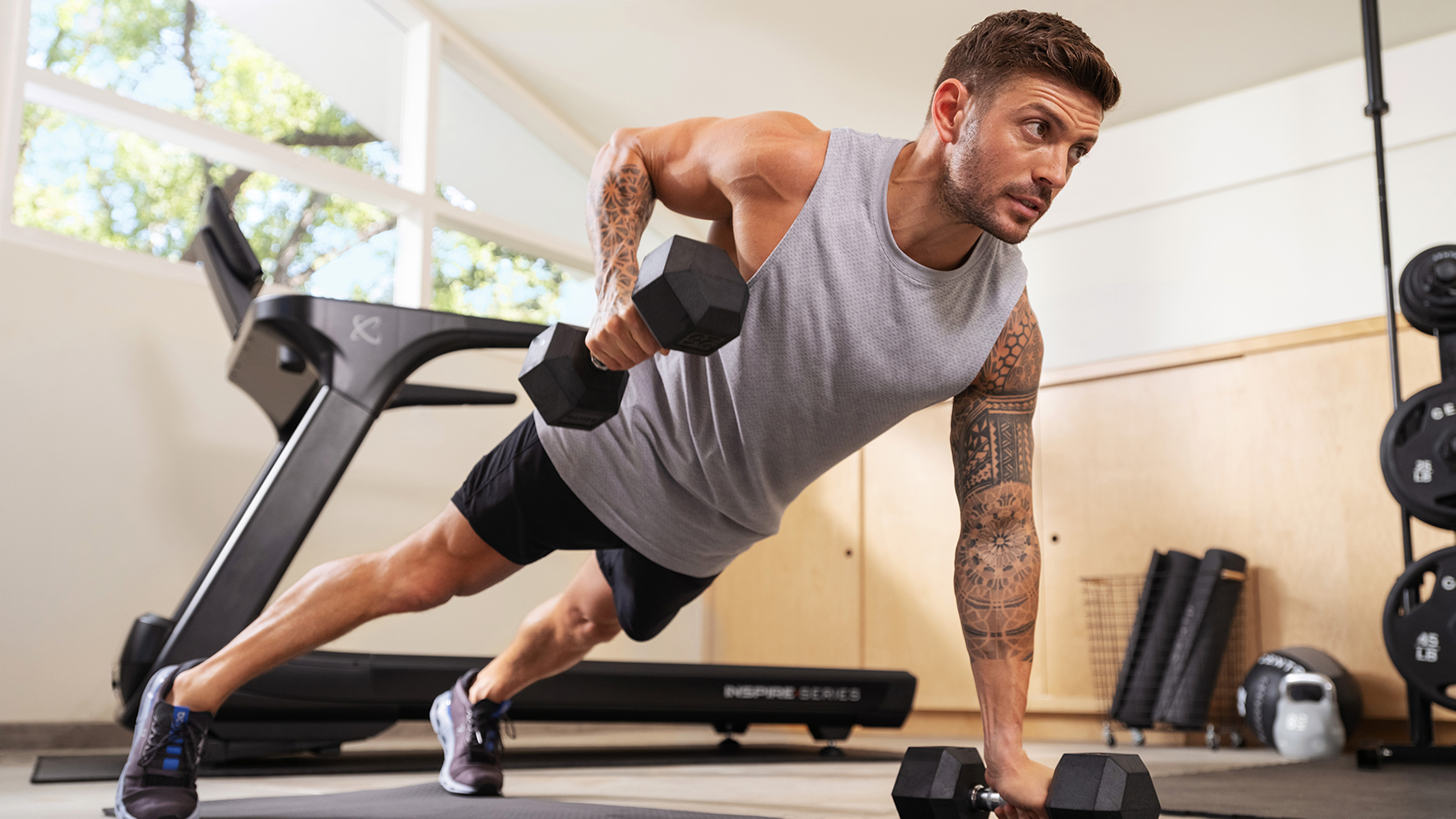 Centr trainer Luke Zocchi performs a dumbbell renegade row on the floor.