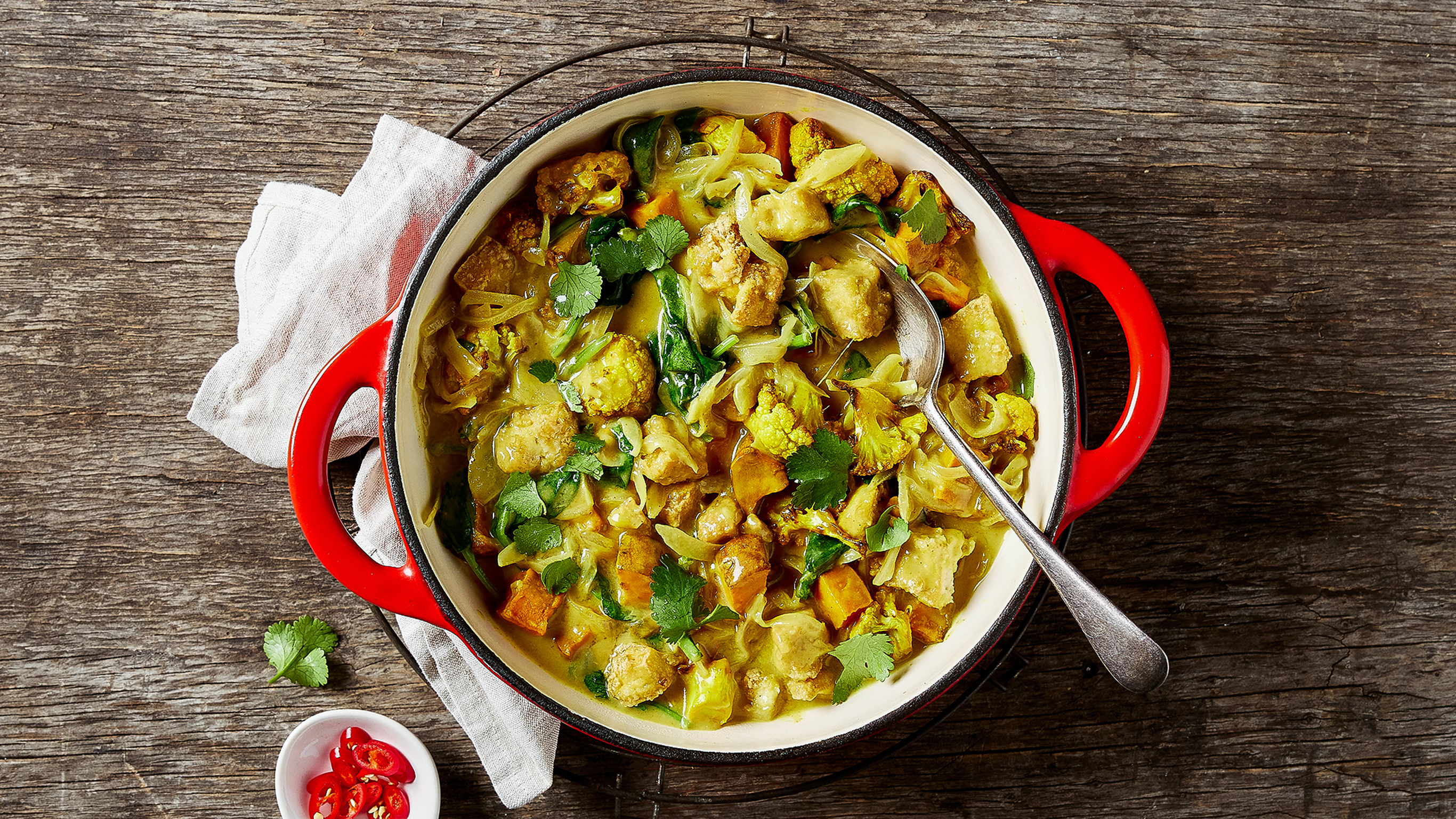 A red enamal pot of Centr's Creamy Roasted Tofu & Cauliflower Korma is ready for serving.