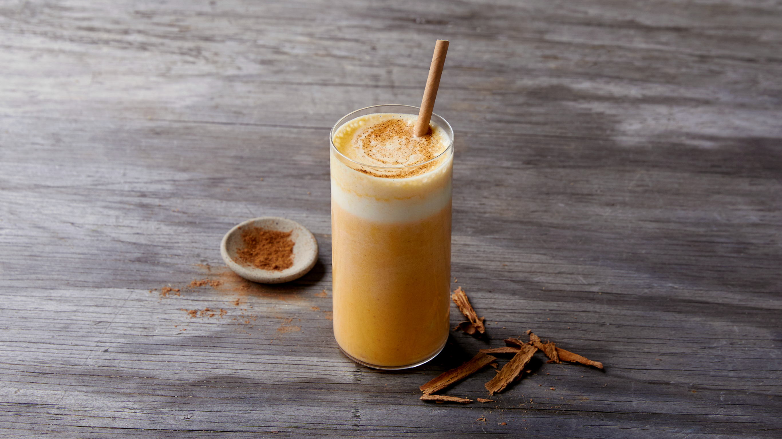A tall glass of golden Pumpkin Spice Smoothie is ready for drinking.