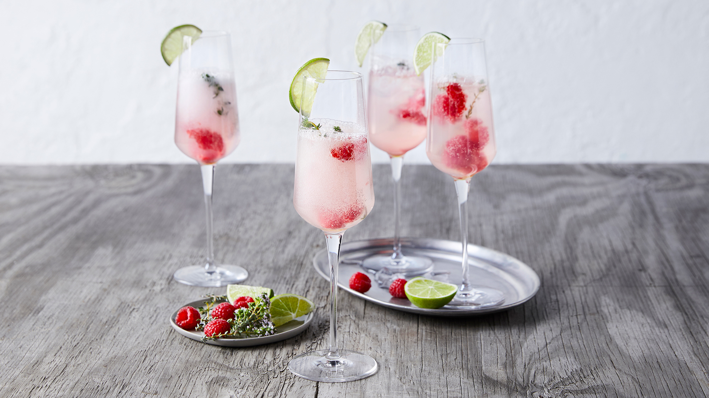 Four champagne flutes of Centr's Raspberry Gin-less Fizz, on a serving tray, are ready for drinking.