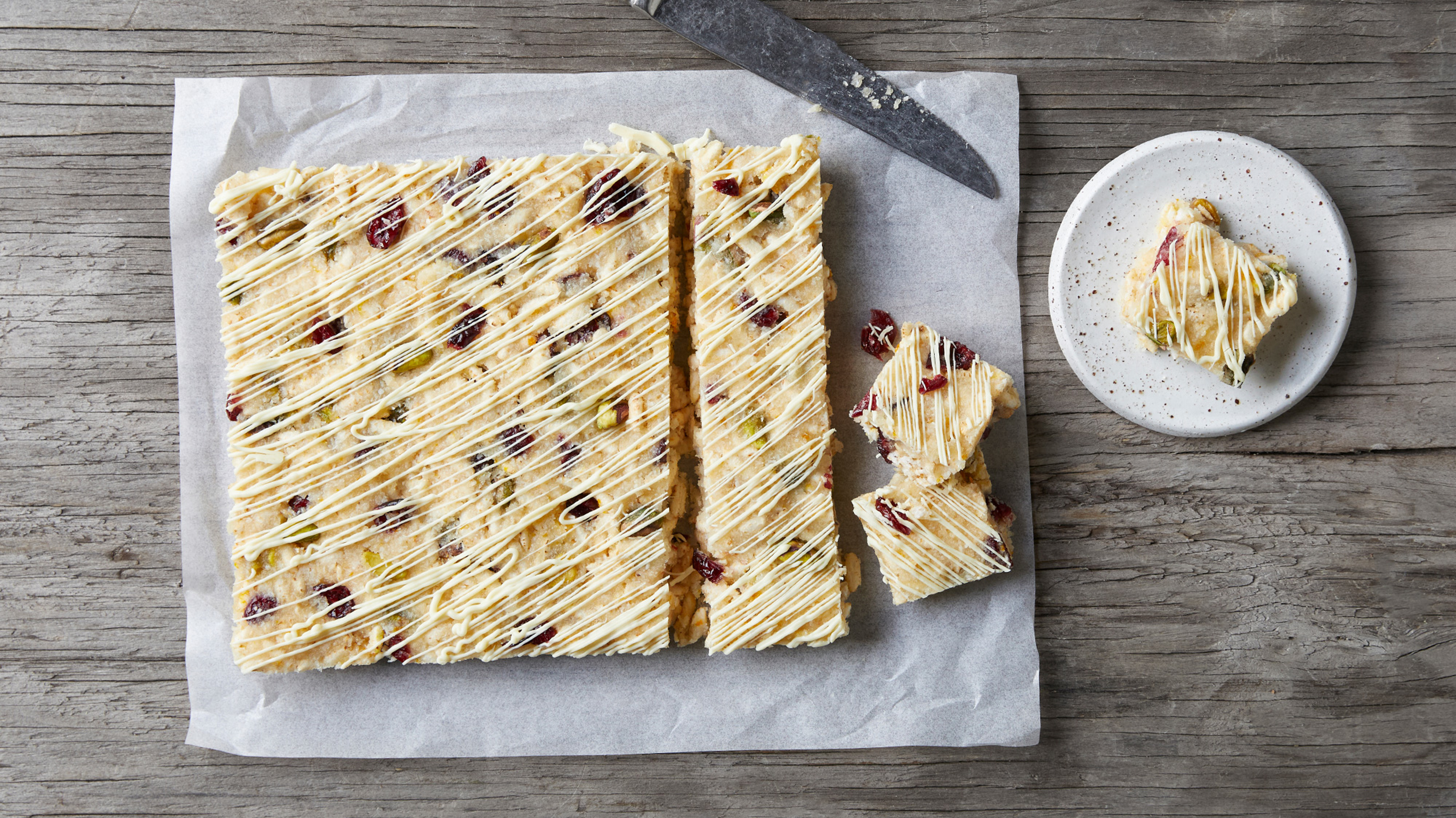 A block of Centr's White Christmas rests on baking paper, with slices and squares cut, ready to eat.