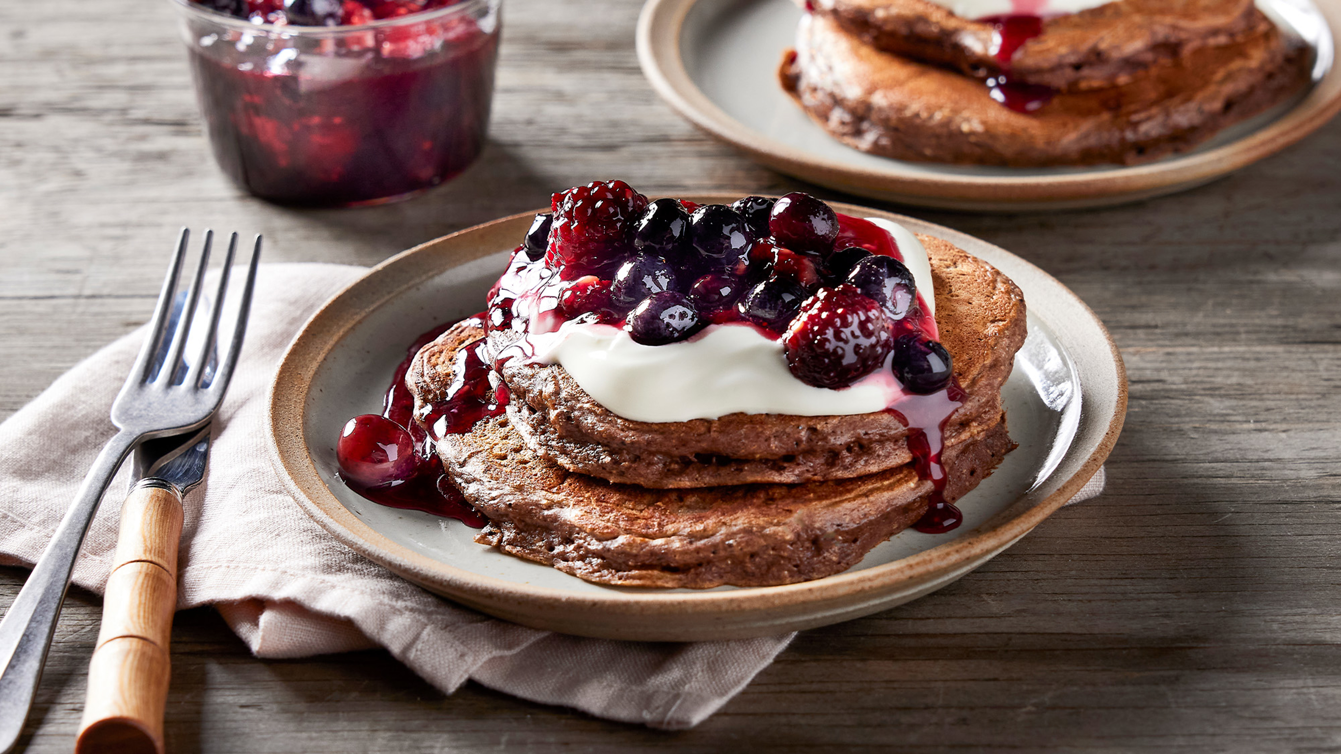 A plate of Chocolate Protein Pancakes with Berries from the Centr menu is ready for eating.
