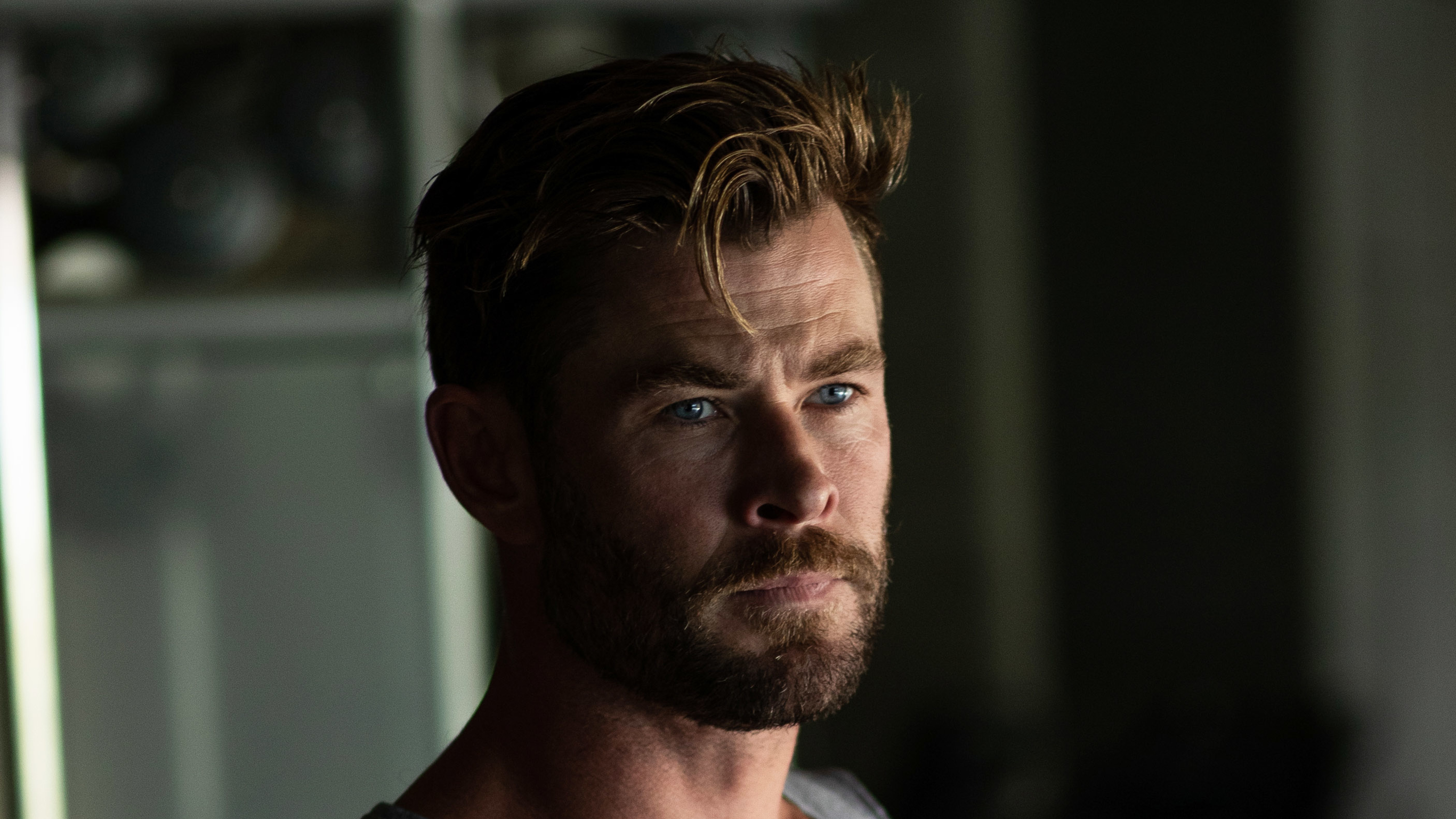 A three quarter angle photo of Chris Hemsworth looking off to one side, past the camera.