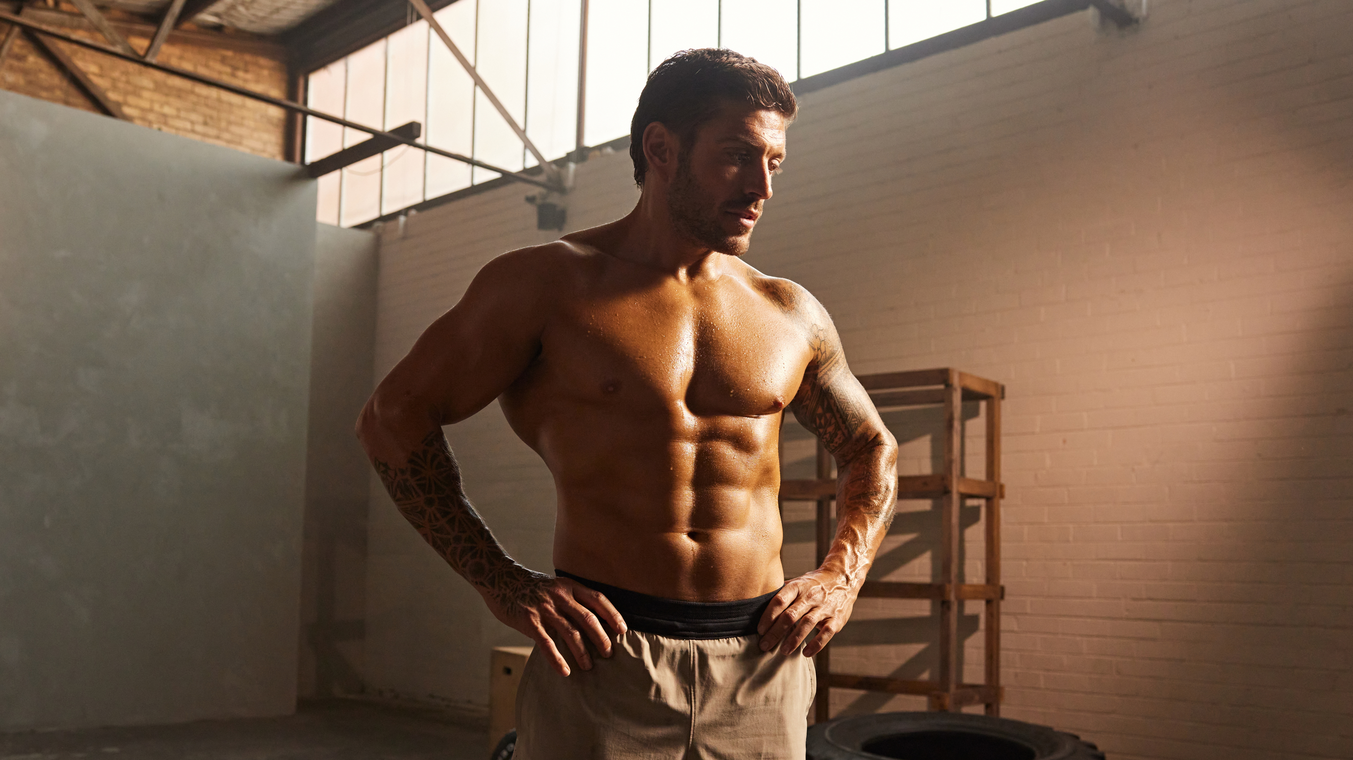 Centr trainer Luke Zocchi stands shirtless with his hands on his hips.
