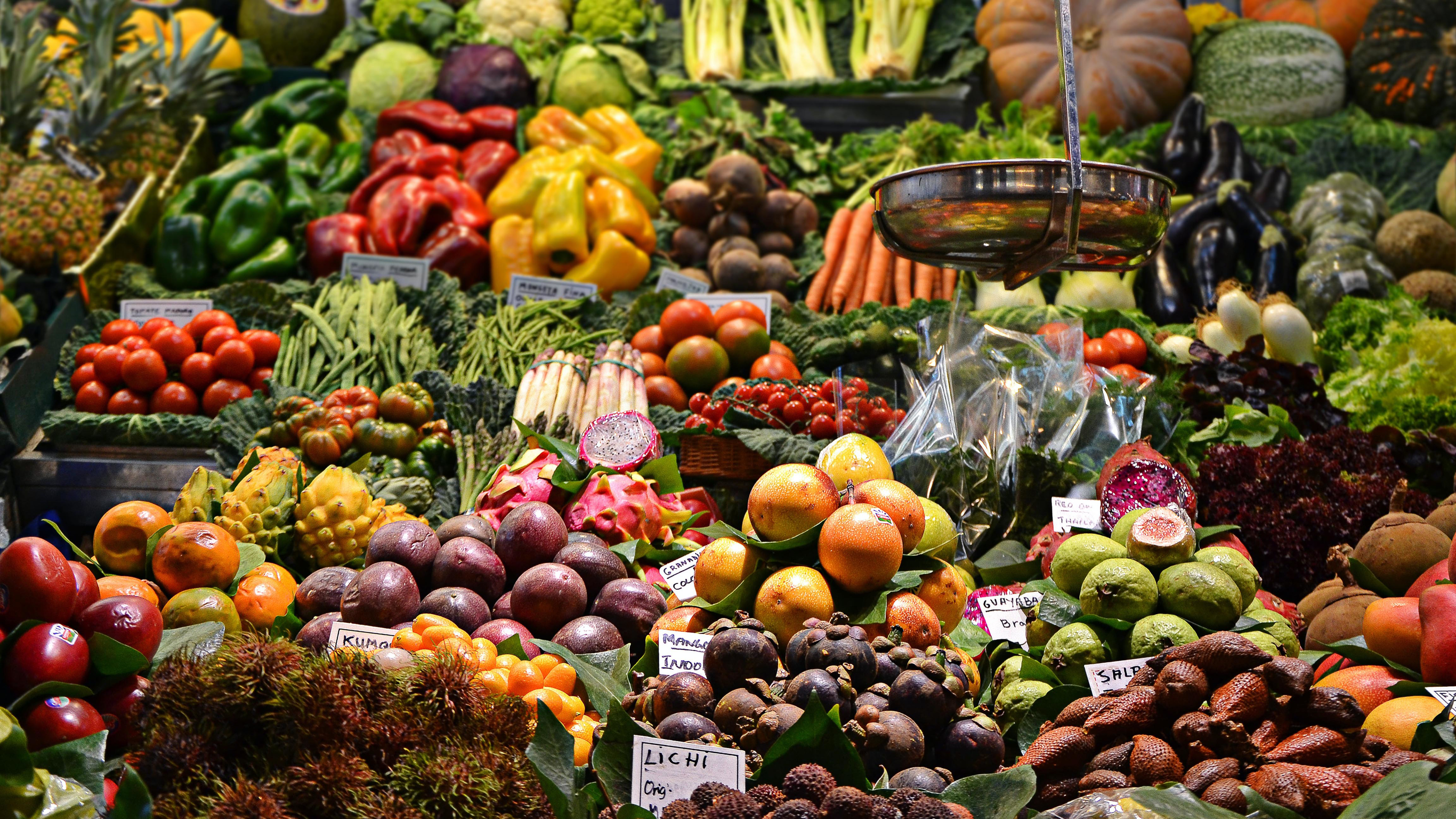 A large display of a large range of fruits and vegetables in a market stand.