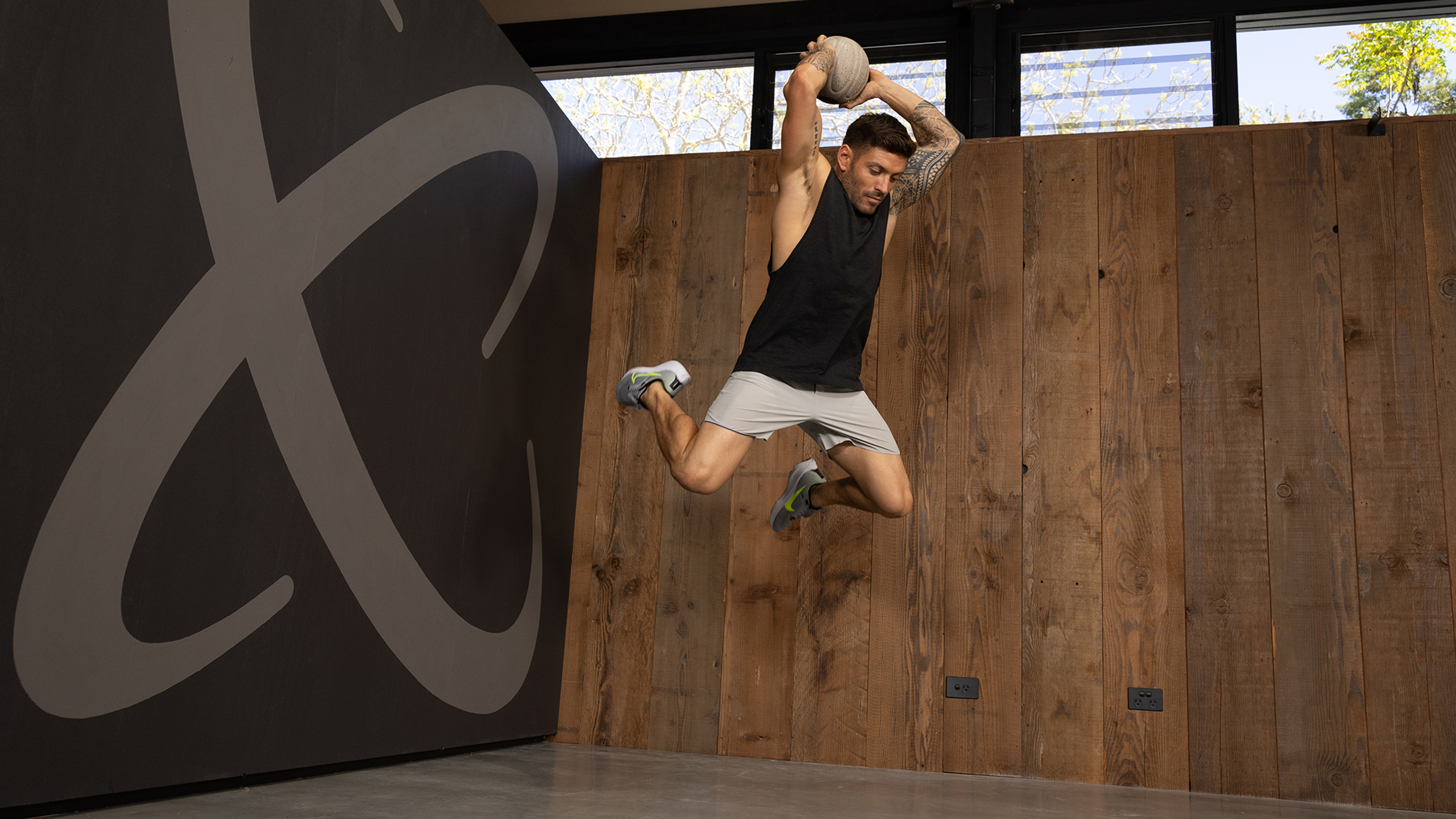Centr trainer Luke Zocchi performs an overhead slam with the slam ball while leaping in the air.