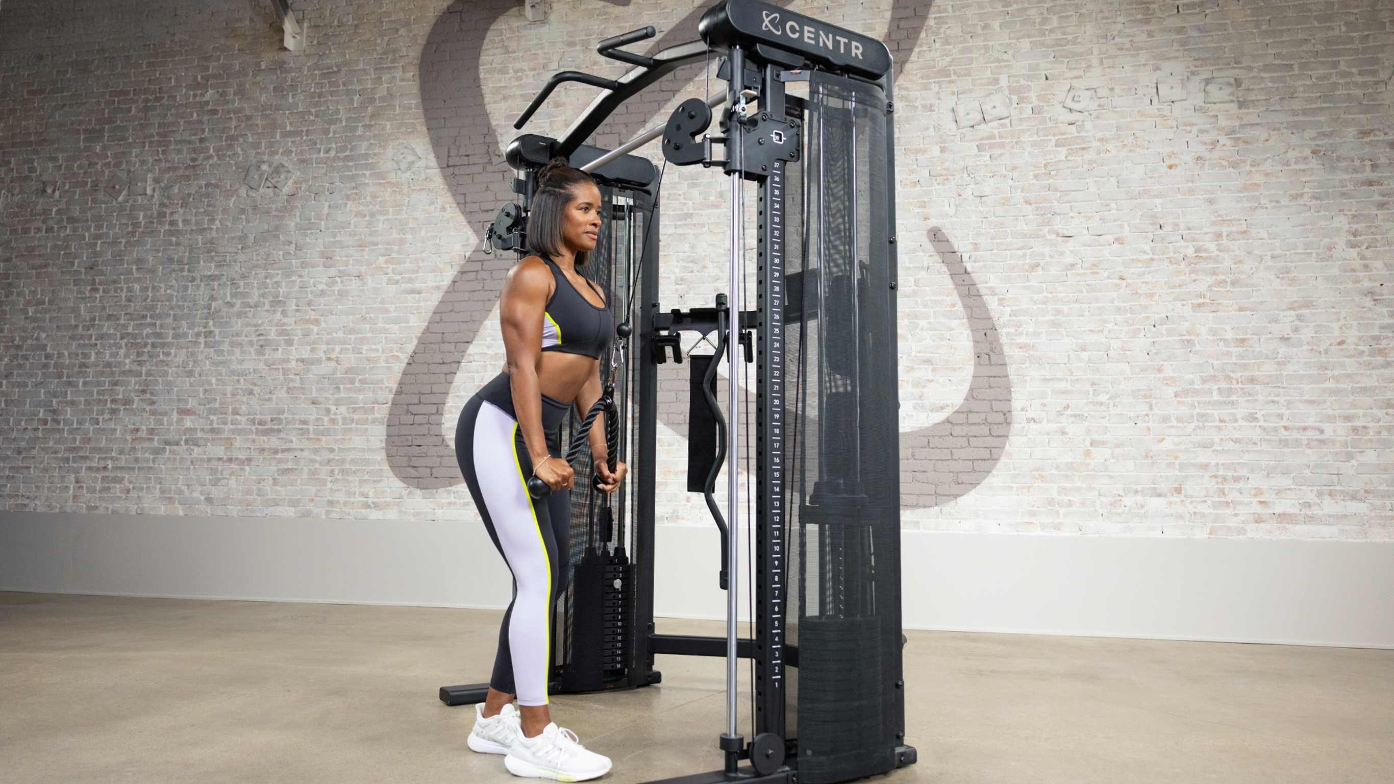 Ingrid Clay performs tricep pulldowns using the bar on the Centr 3 Home Gym Functional Trainer.