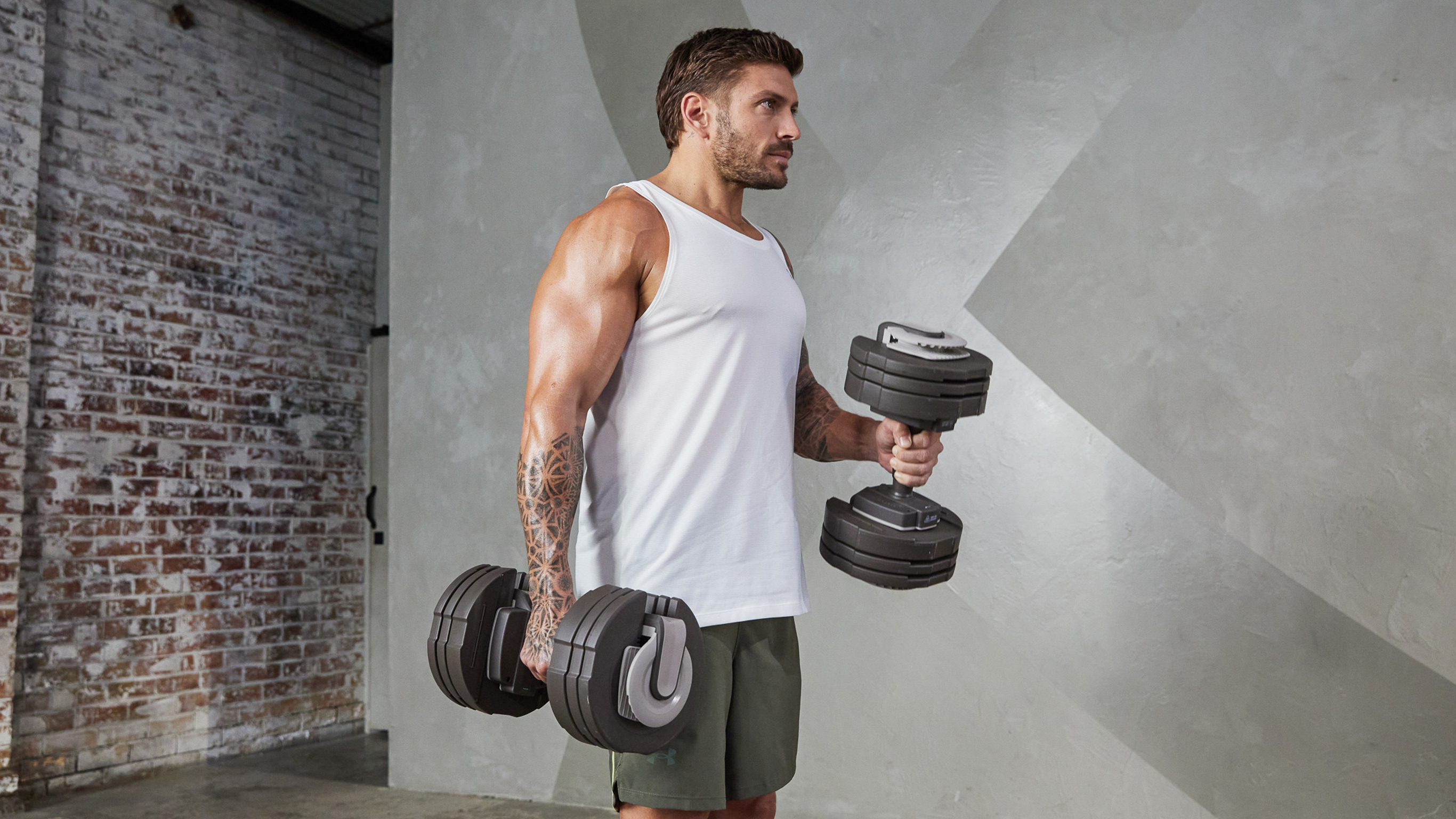 Luke Zocchi performs bicep curls, looking strong and muscular.