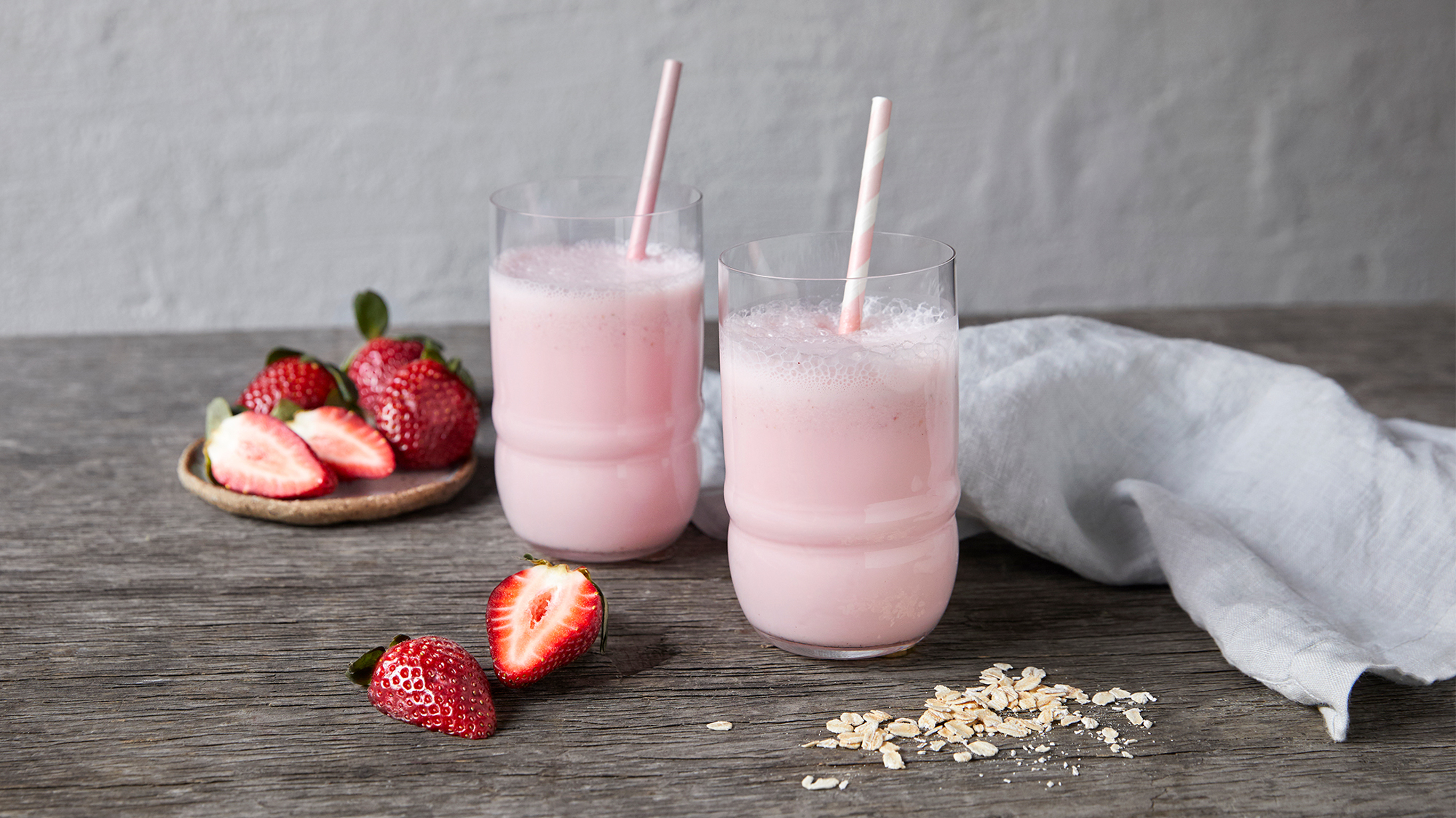 Two glasses of pink, frothy Creamy Strawberry Smoothie from the Centr menu are reading for drinking.