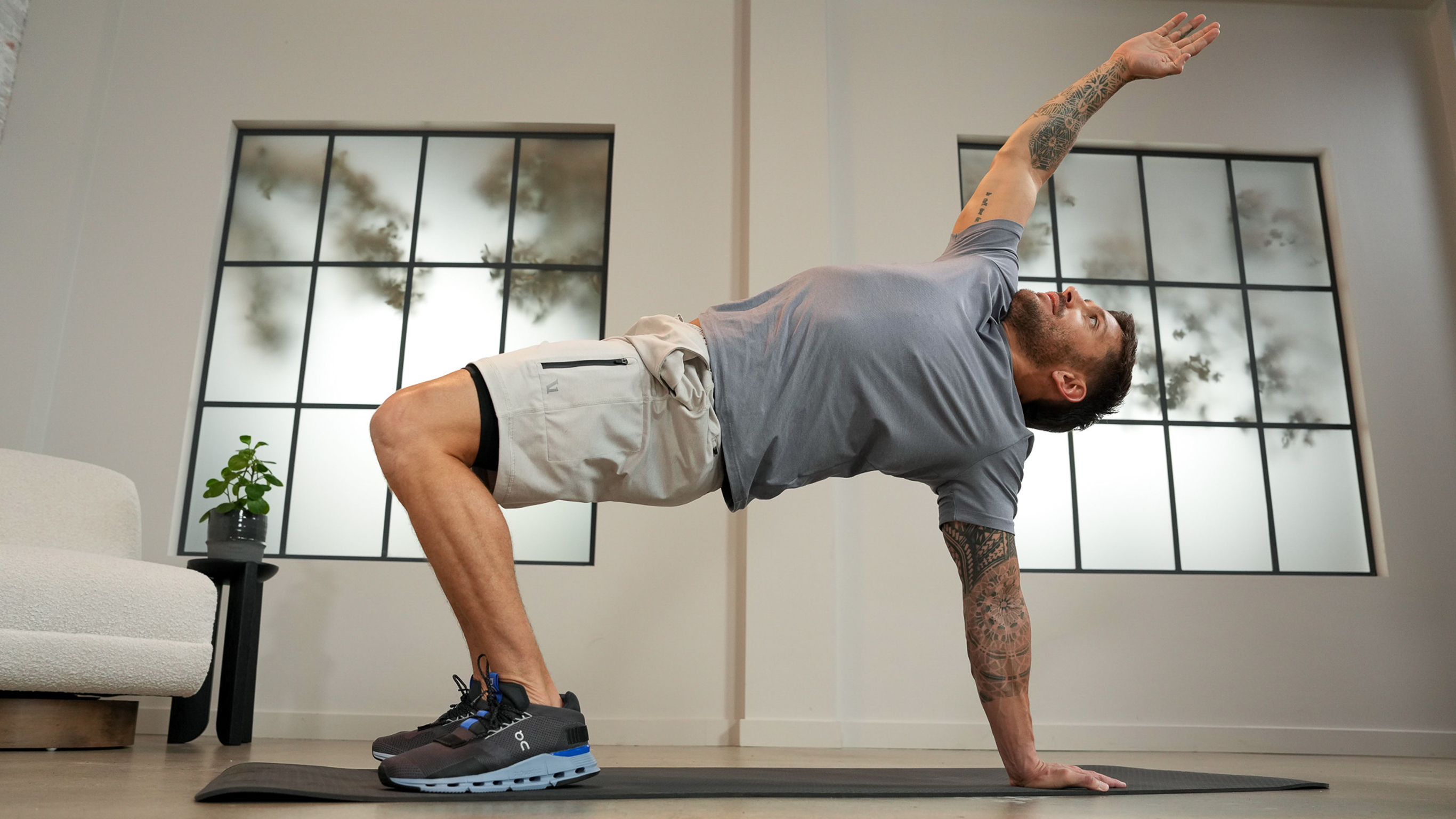 Luke Zocchi, in grey gym gear, performs a reverse plank arm extension stretch