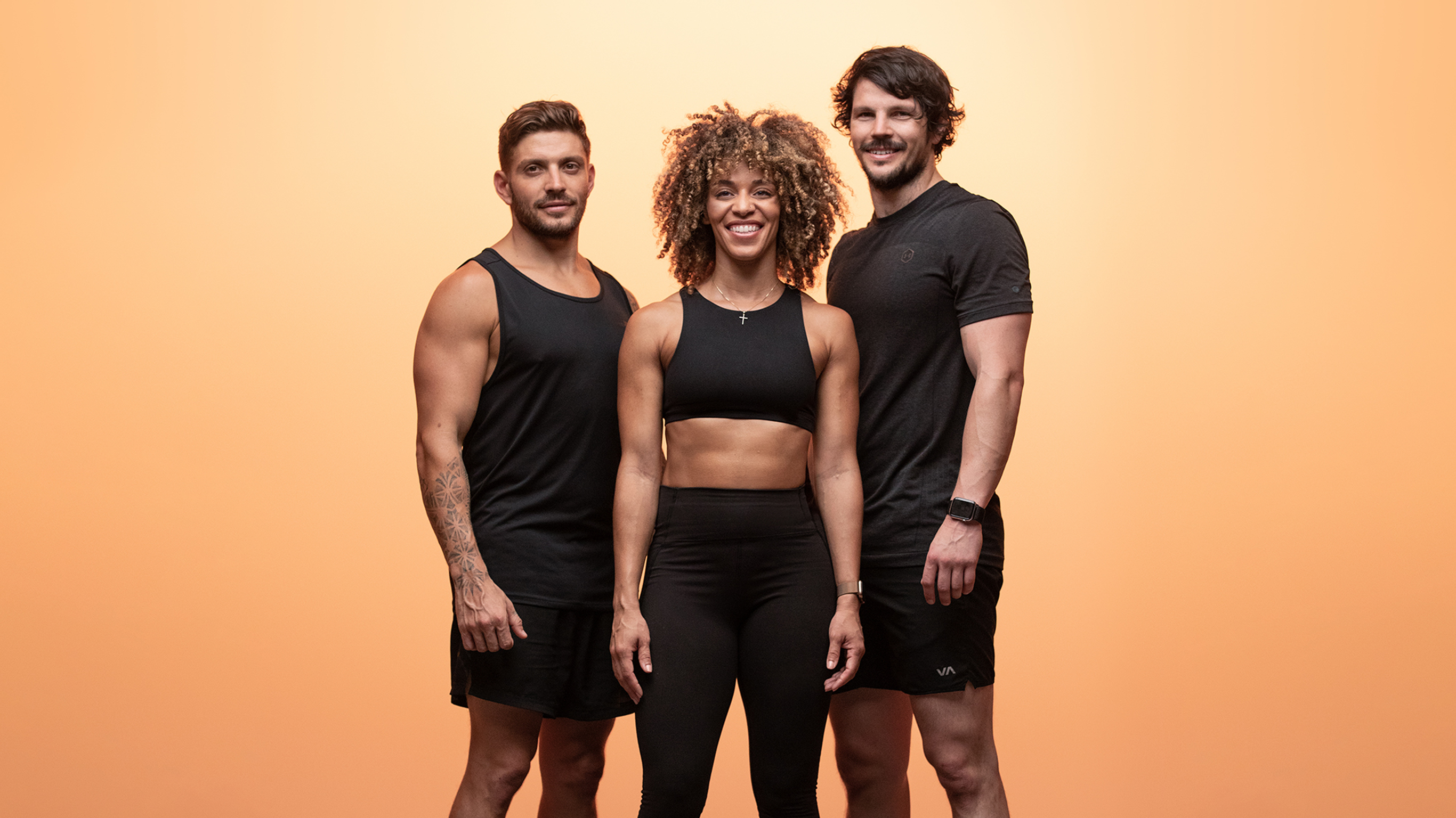 Luke Zocchi, Dan Churchill and Ashley Joi pose together in gym clothes, looking at the camera and smiling